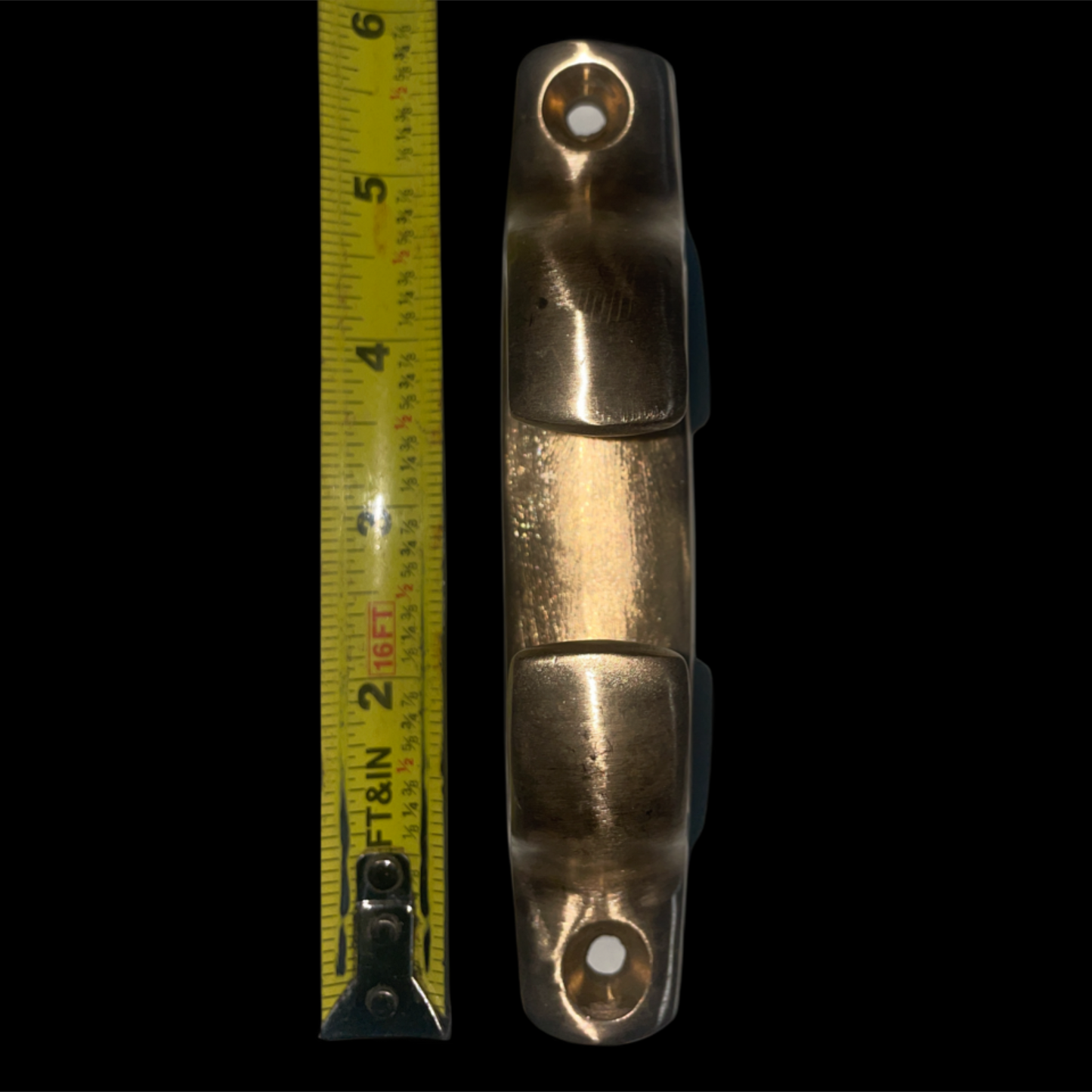 Bronze clevis with a measuring tape on a black background