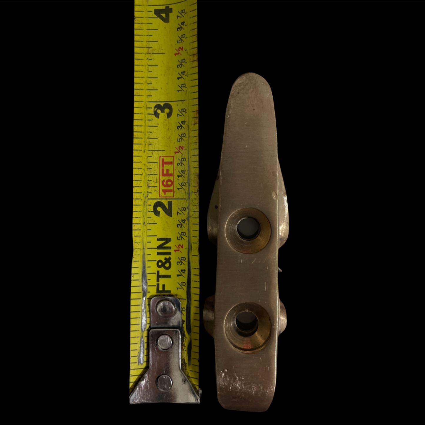 Metal cleat with a measuring tape on a black background