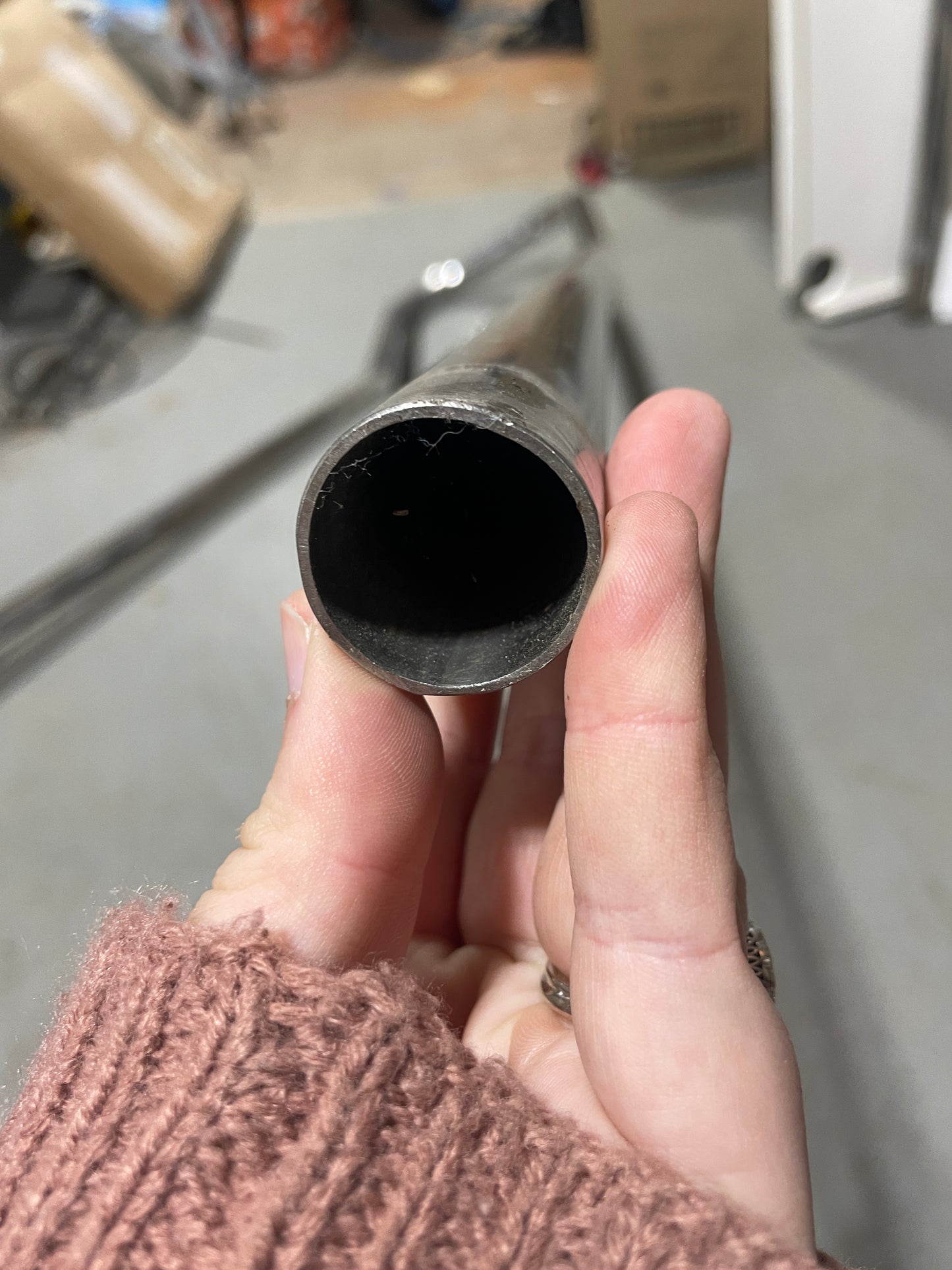 Hand holding a metal pipe with a blurred background