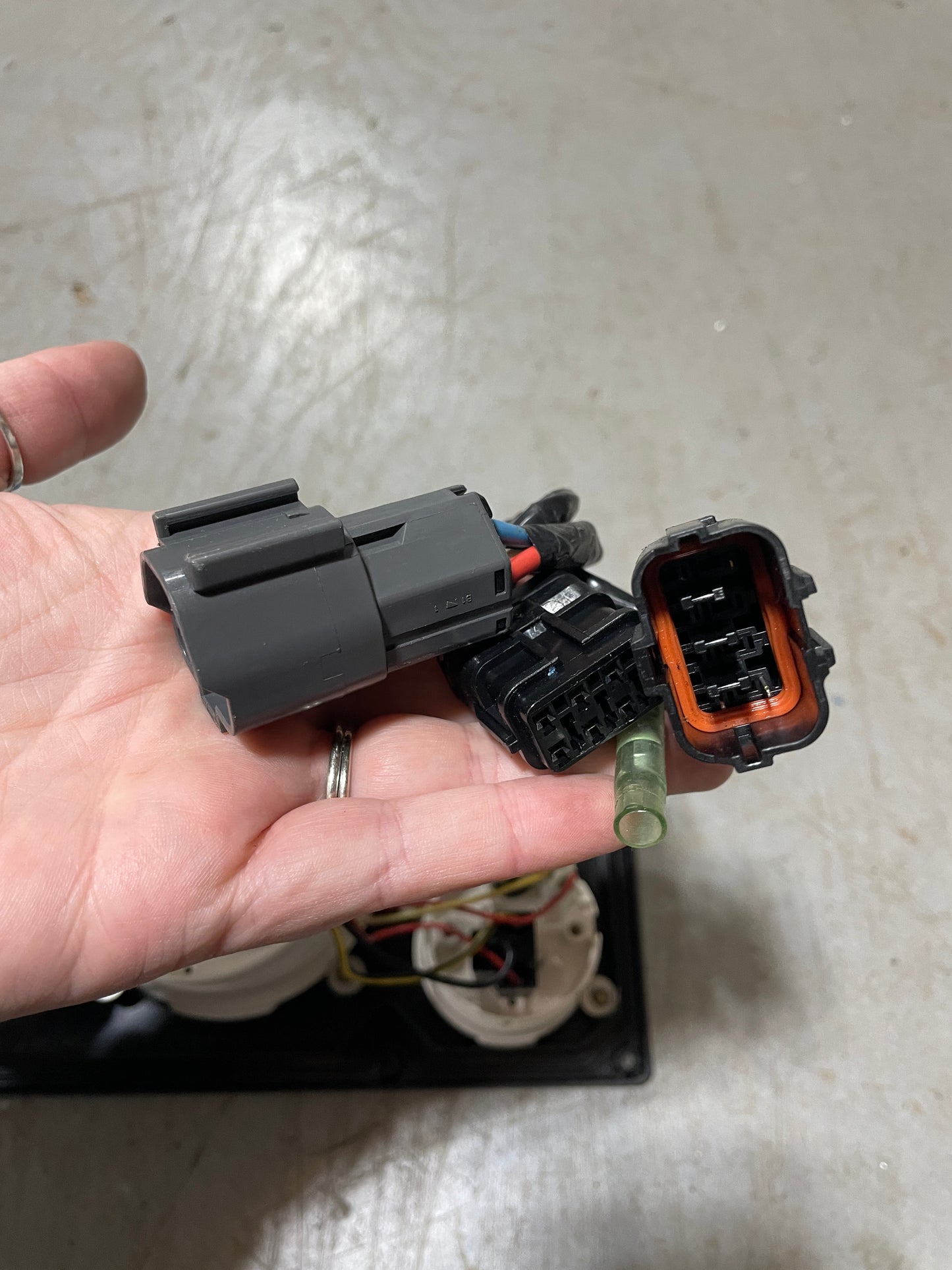 Hand holding a black electrical connector against a light gray background