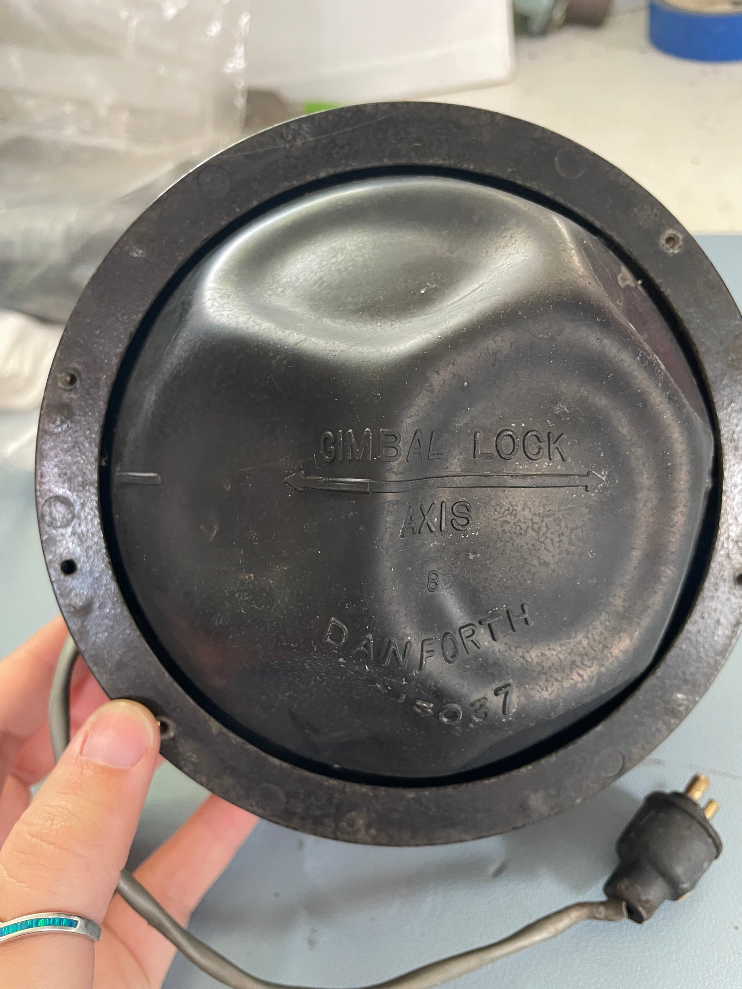 Round metal cover with 'Danelectro' branding held by a hand against a blurred background