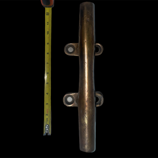 Metal cleat with a measuring tape for scale on a black background