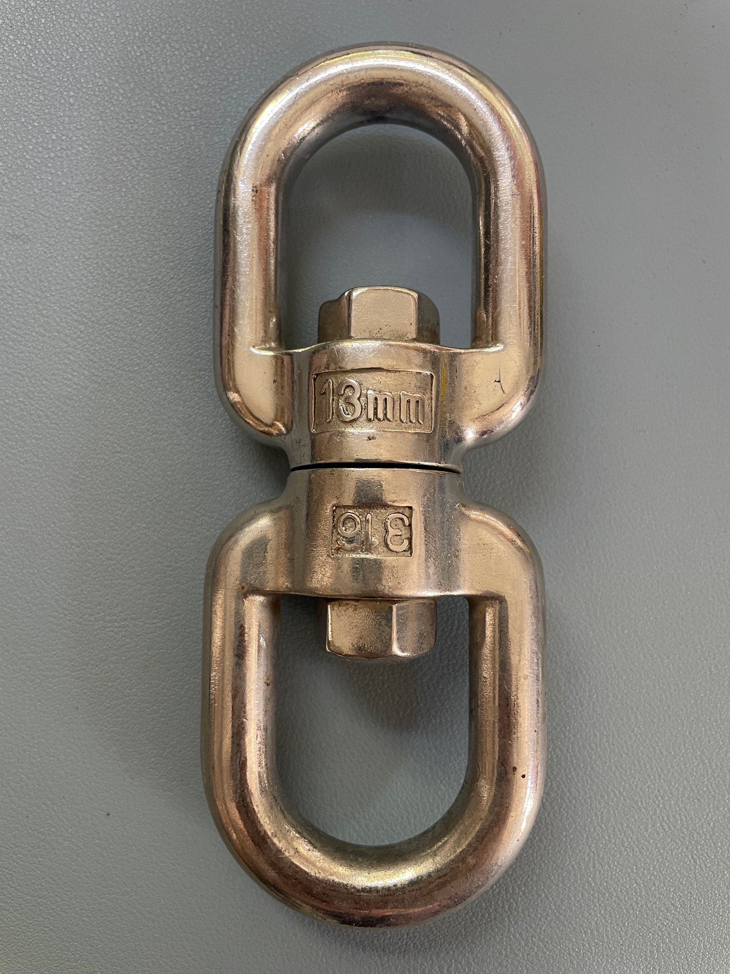 Bronze metal swivel eye bolt on a gray background