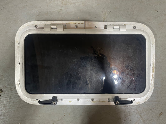 Rectangular metal window with a dark glass pane on a gray surface