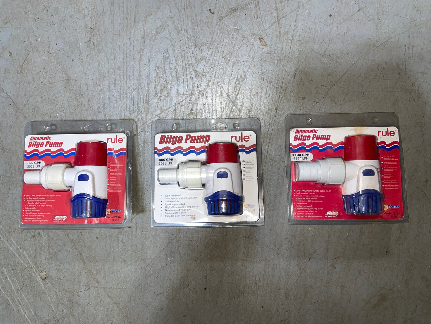 Three packages of Rule bilge pumps on a gray surface