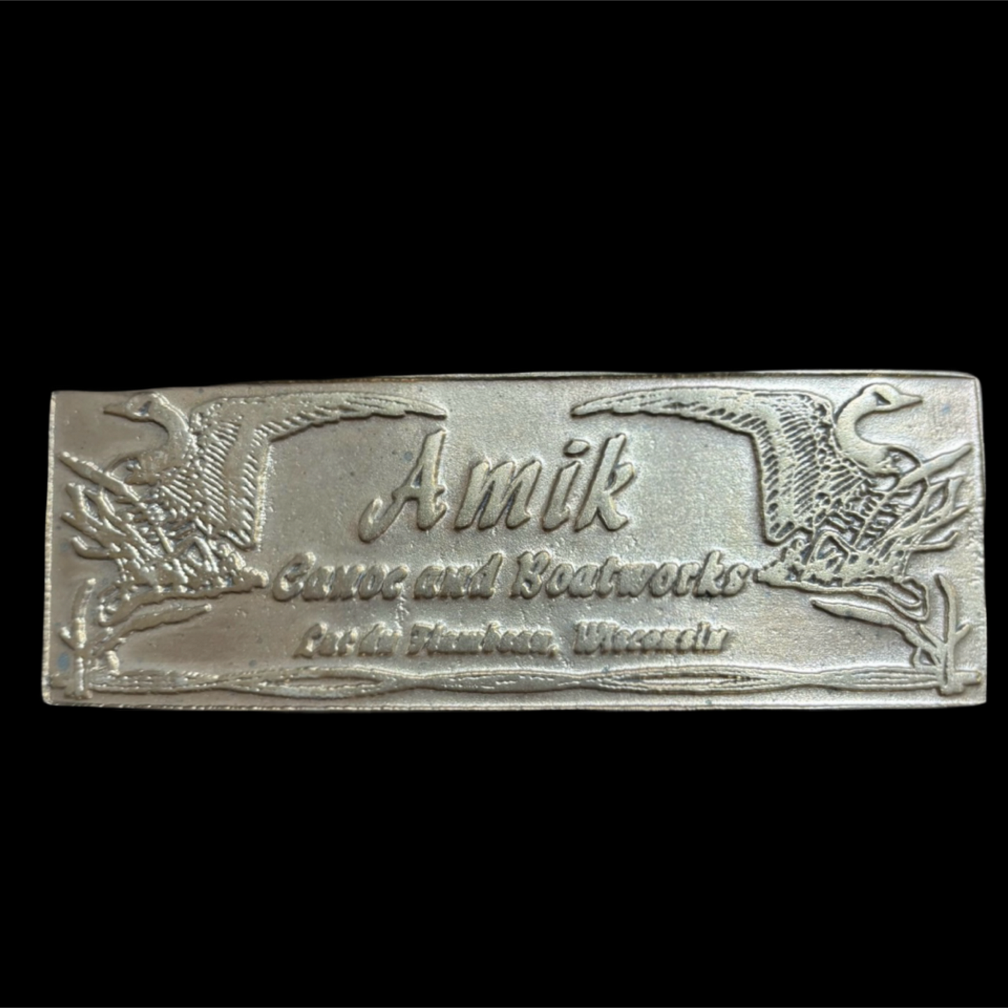 bronze builders plate with 'Amik' branding on a black background