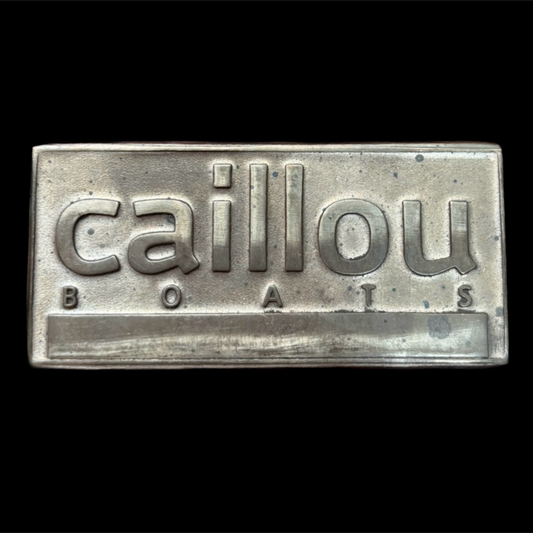 Metallic sign with 'caillou BOATS' text on a black background