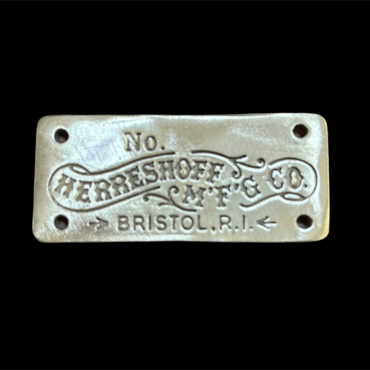 Metallic plaque with 'Herreshoff Mfg. Co.' text on a black background