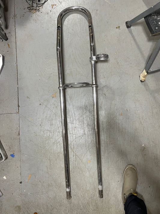 Chrome motorcycle fork on a concrete floor with a person's foot in the background