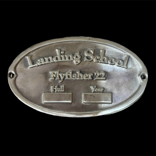 Metal plaque with 'Landing School Flyfisher 22' text on a black background