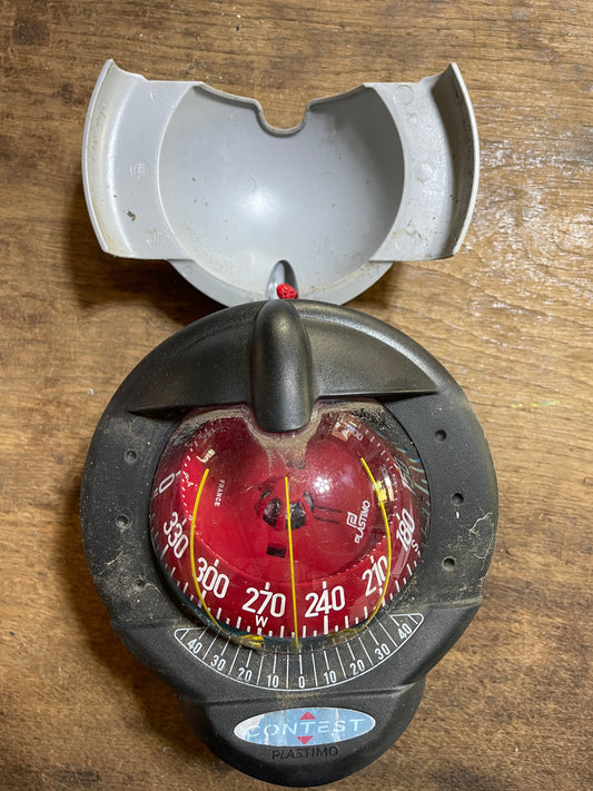 Compass with a red dial on a wooden surface