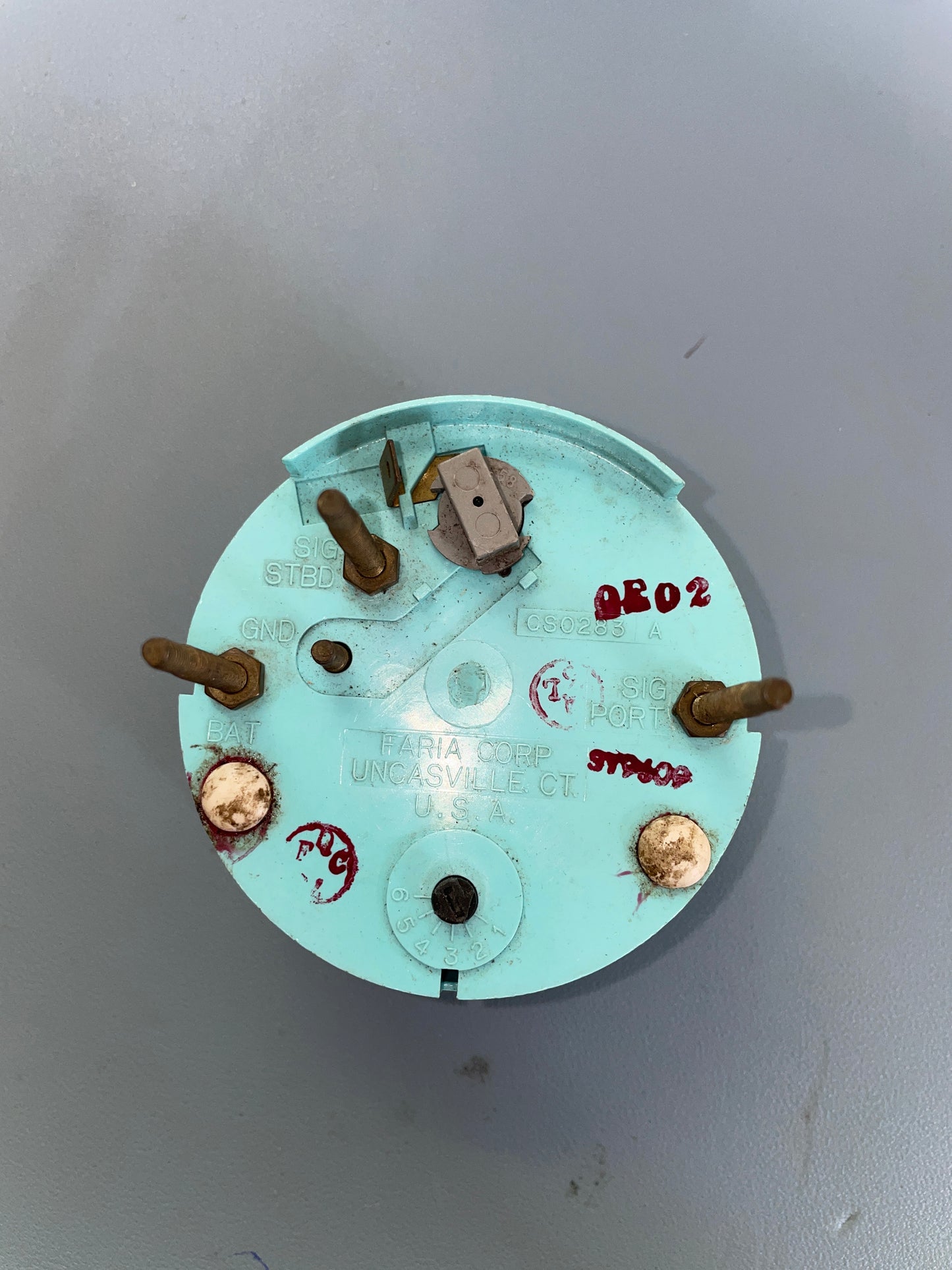 Round mechanical component with text and screws on a gray background