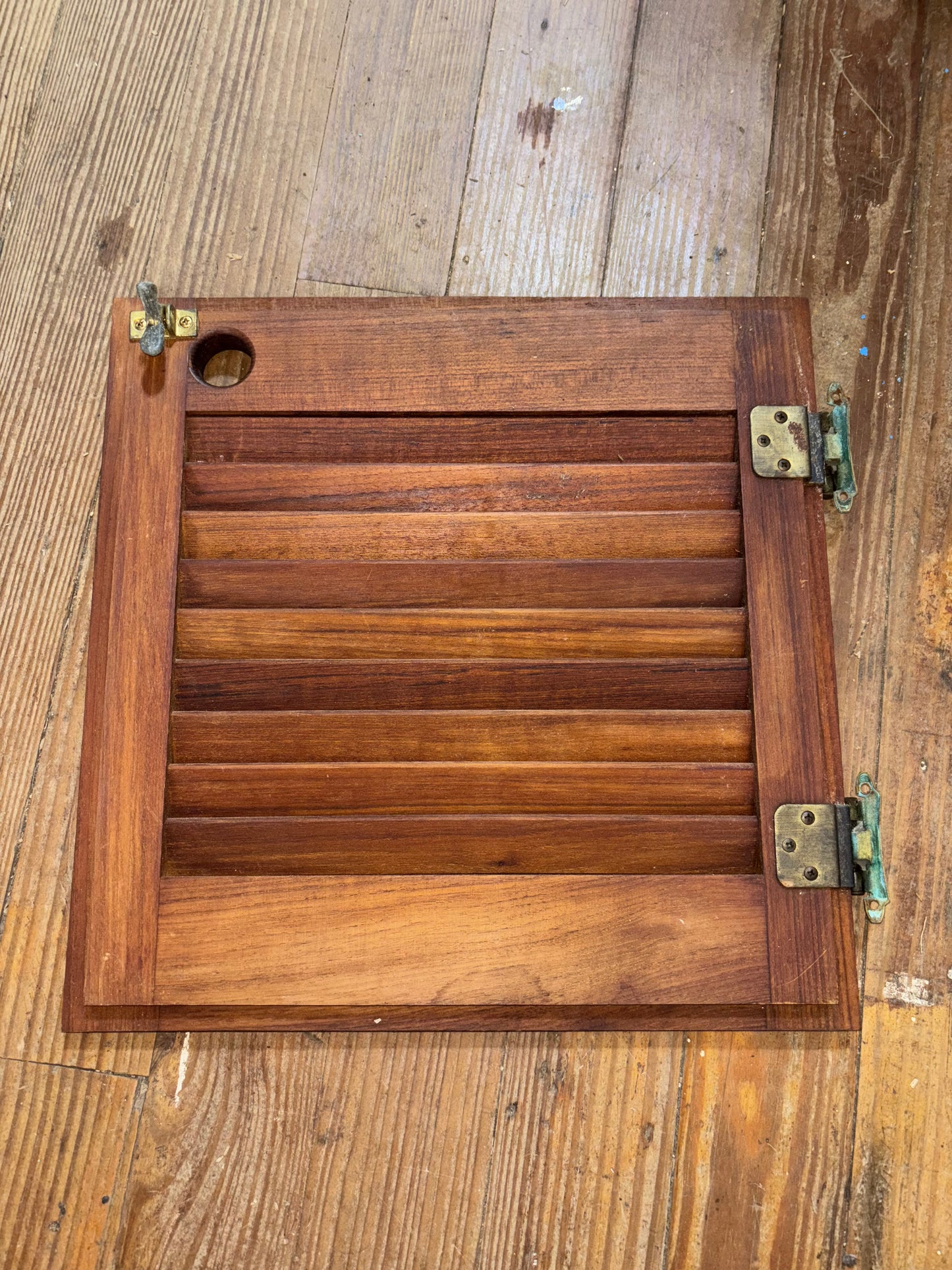 Wooden panel with metal hinges on a wooden background