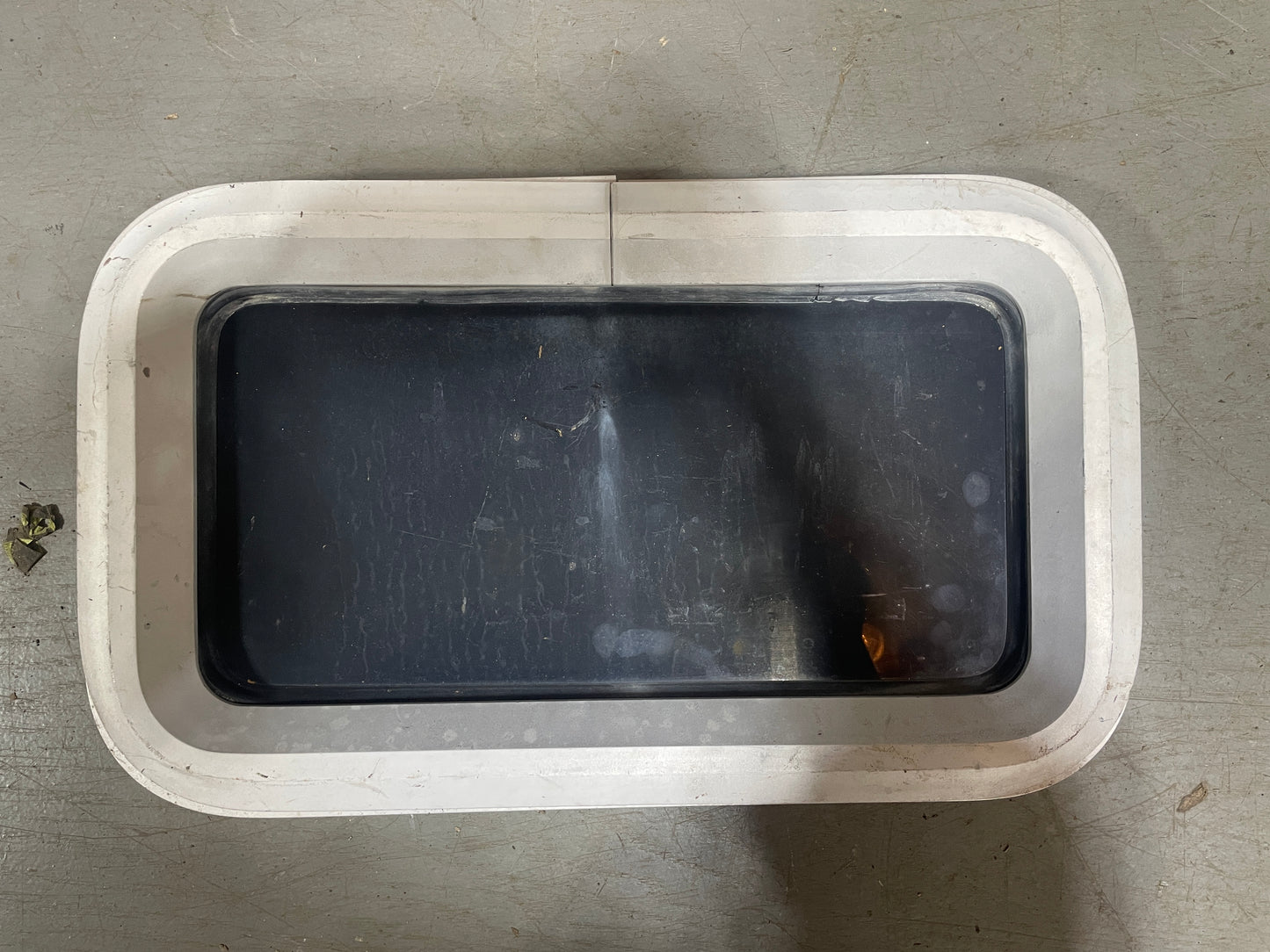 Rectangular metal container with a black interior on a gray concrete surface