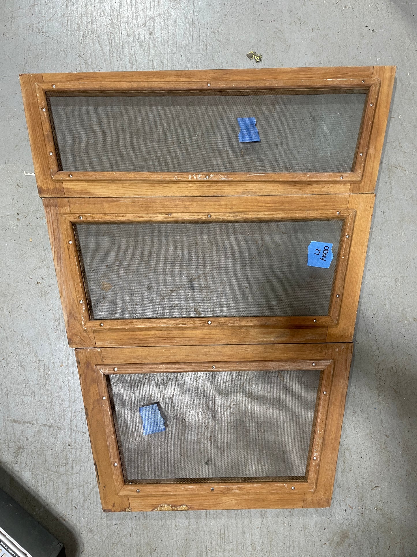 Three wooden screen doors on a concrete floor