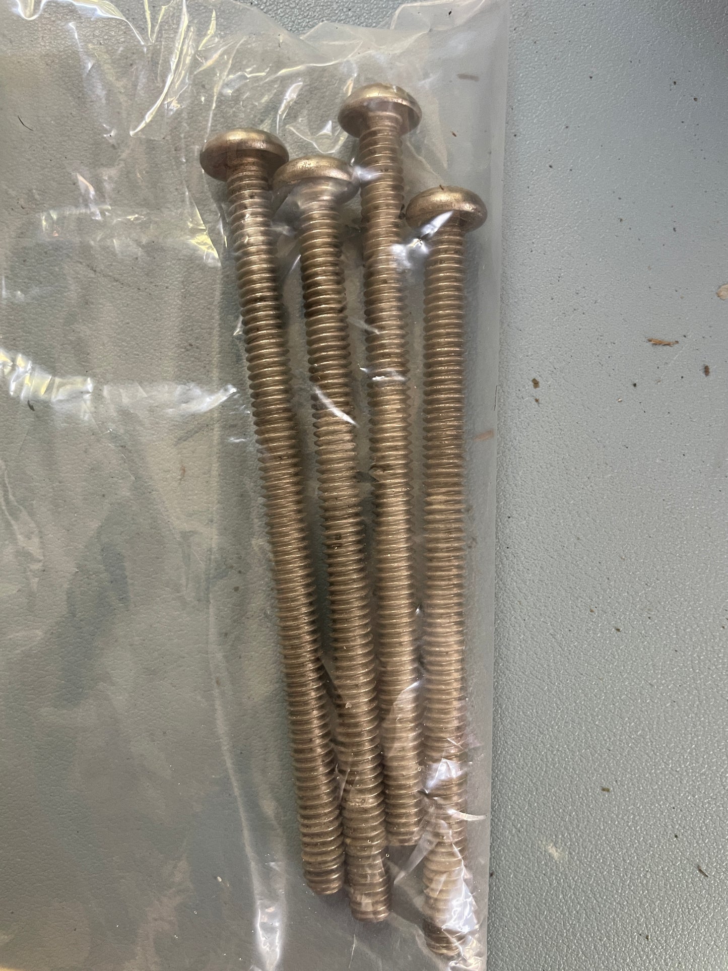 Set of screws in a clear plastic bag on a gray surface