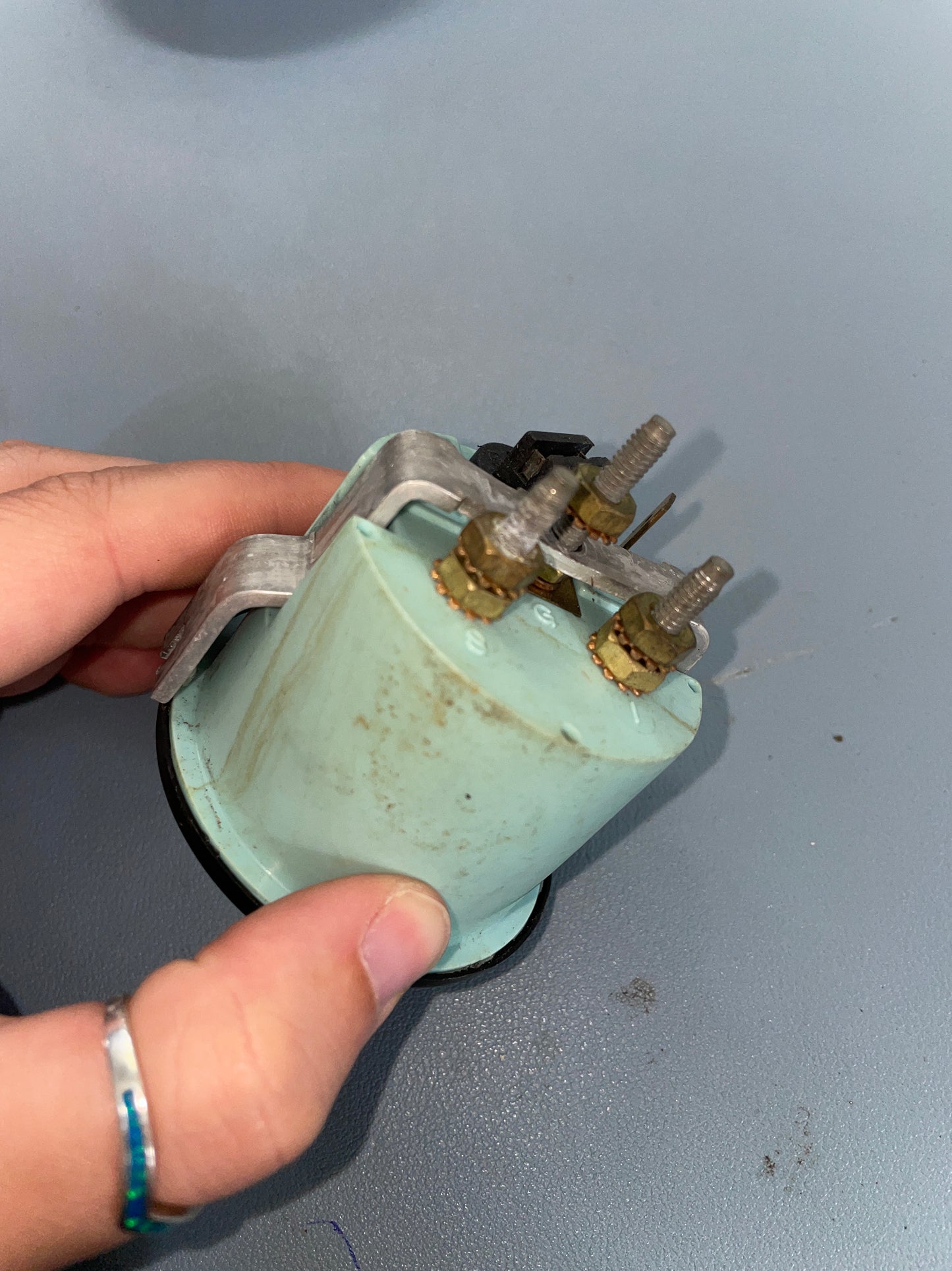 Hand holding a mechanical component against a gray background