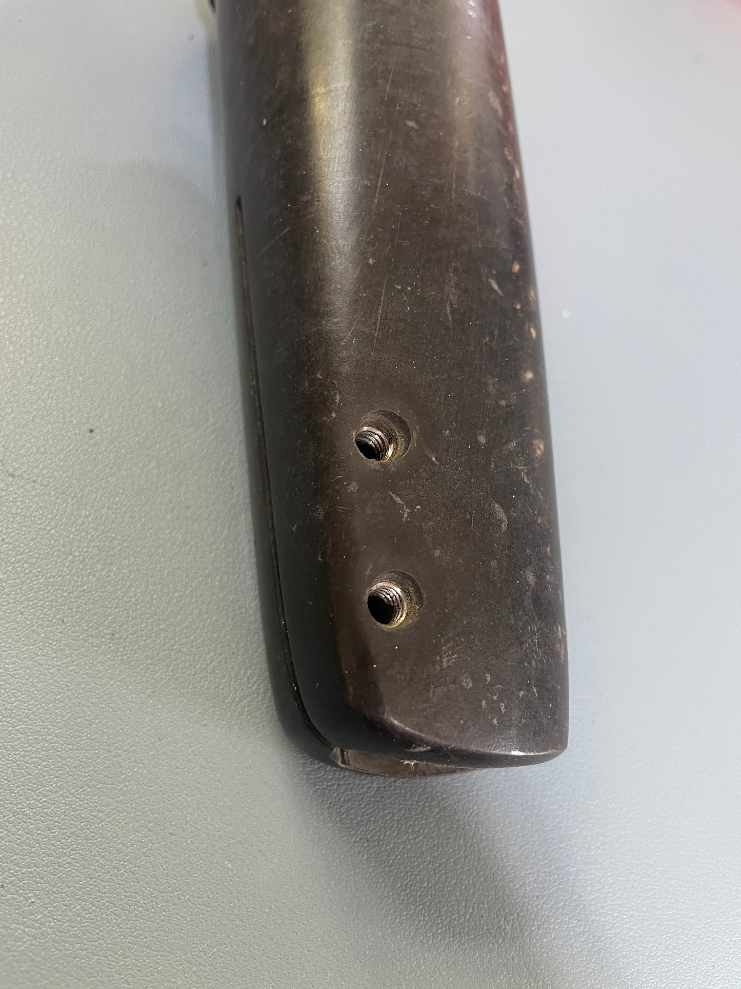 Close-up of a brown leather wallet with metal grommets on a light gray background