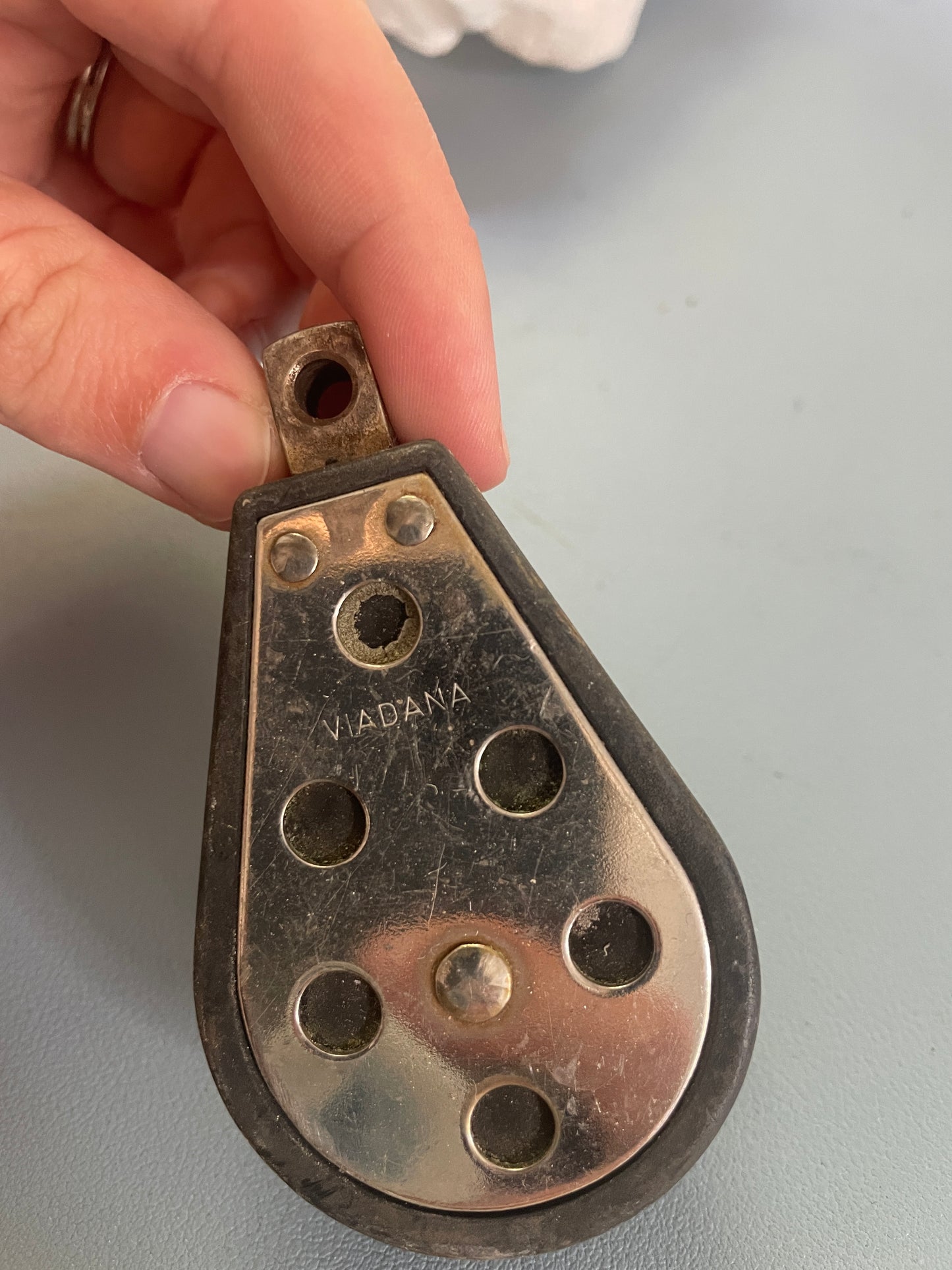 Metal pulley with 'Nadana' branding held by a hand against a gray background