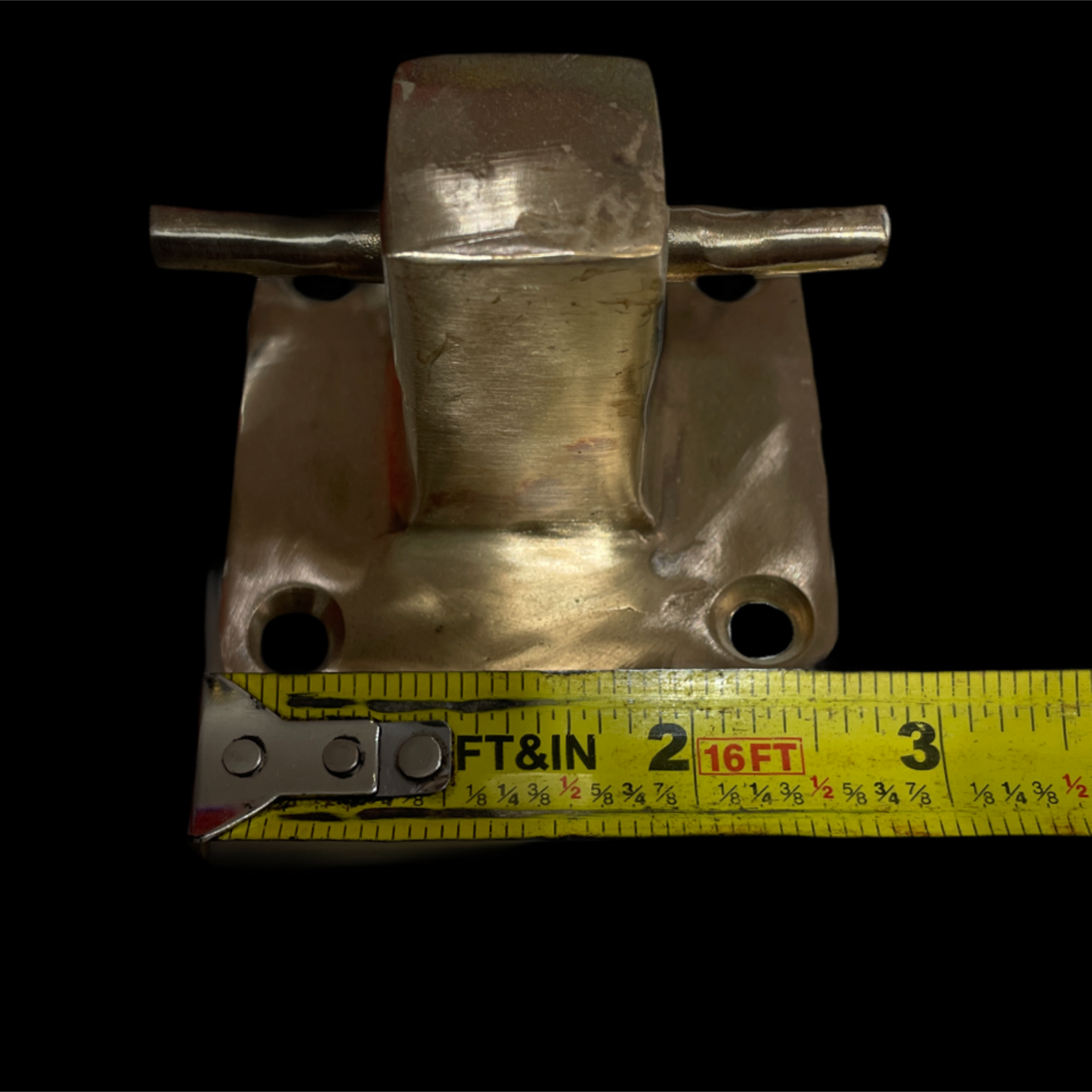 Metal bracket with a tape measure for scale on a black background