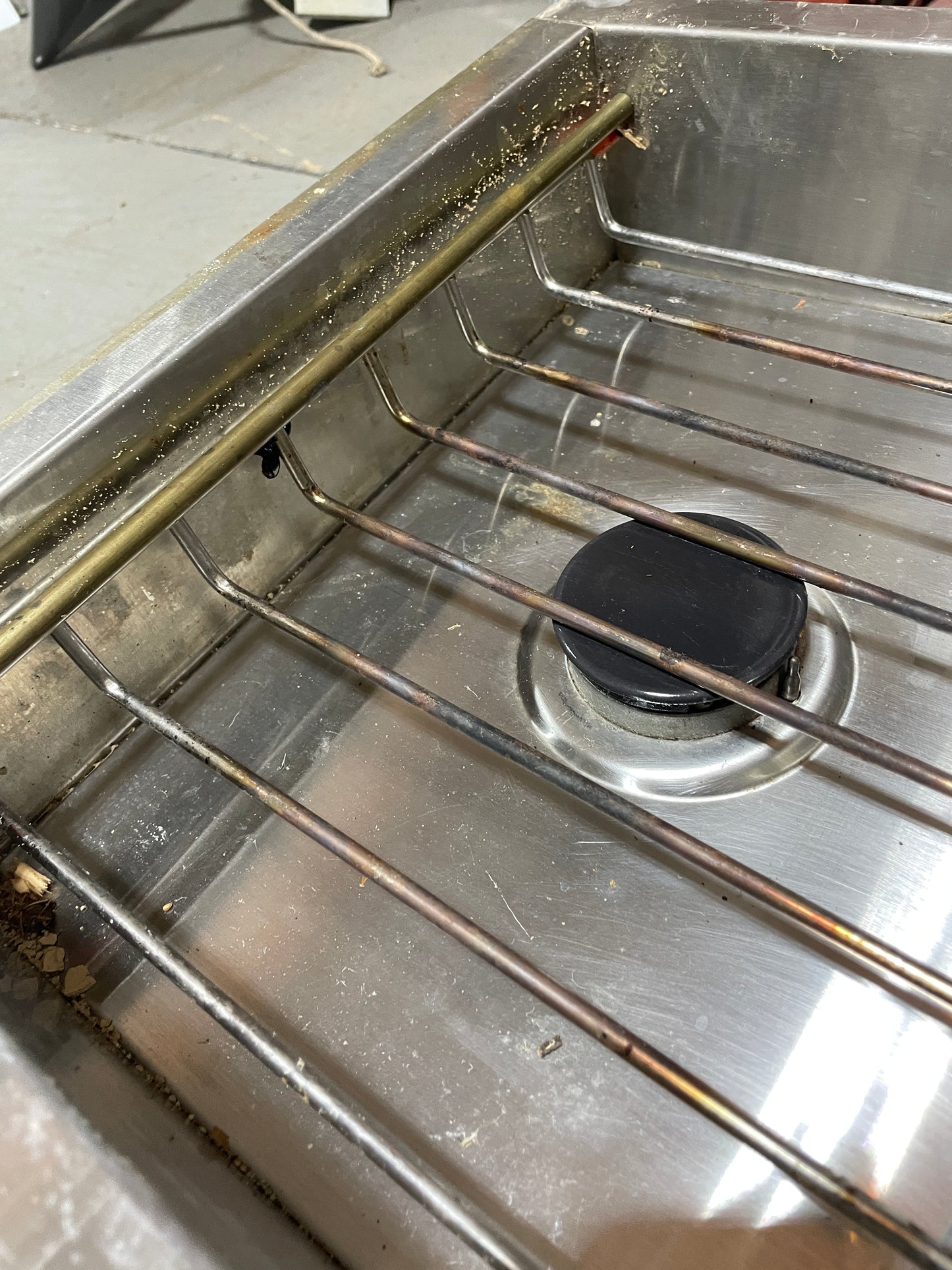 Stainless steel oven rack with a black knob on a metallic surface