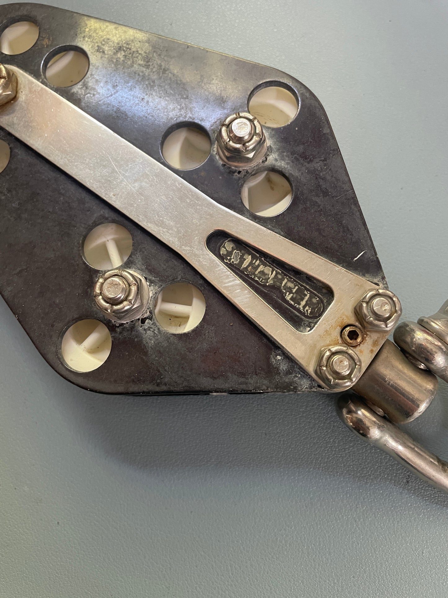 Metal tool with screws and a brand logo on a gray background
