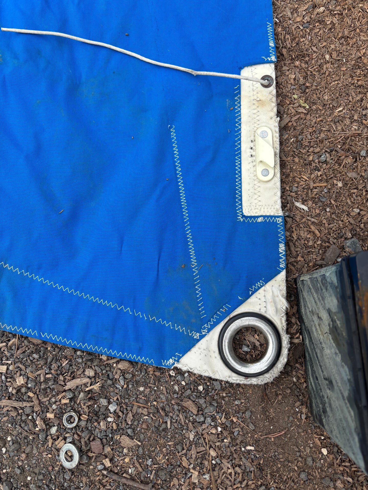 Blue tarp with metal grommets on a dirt ground