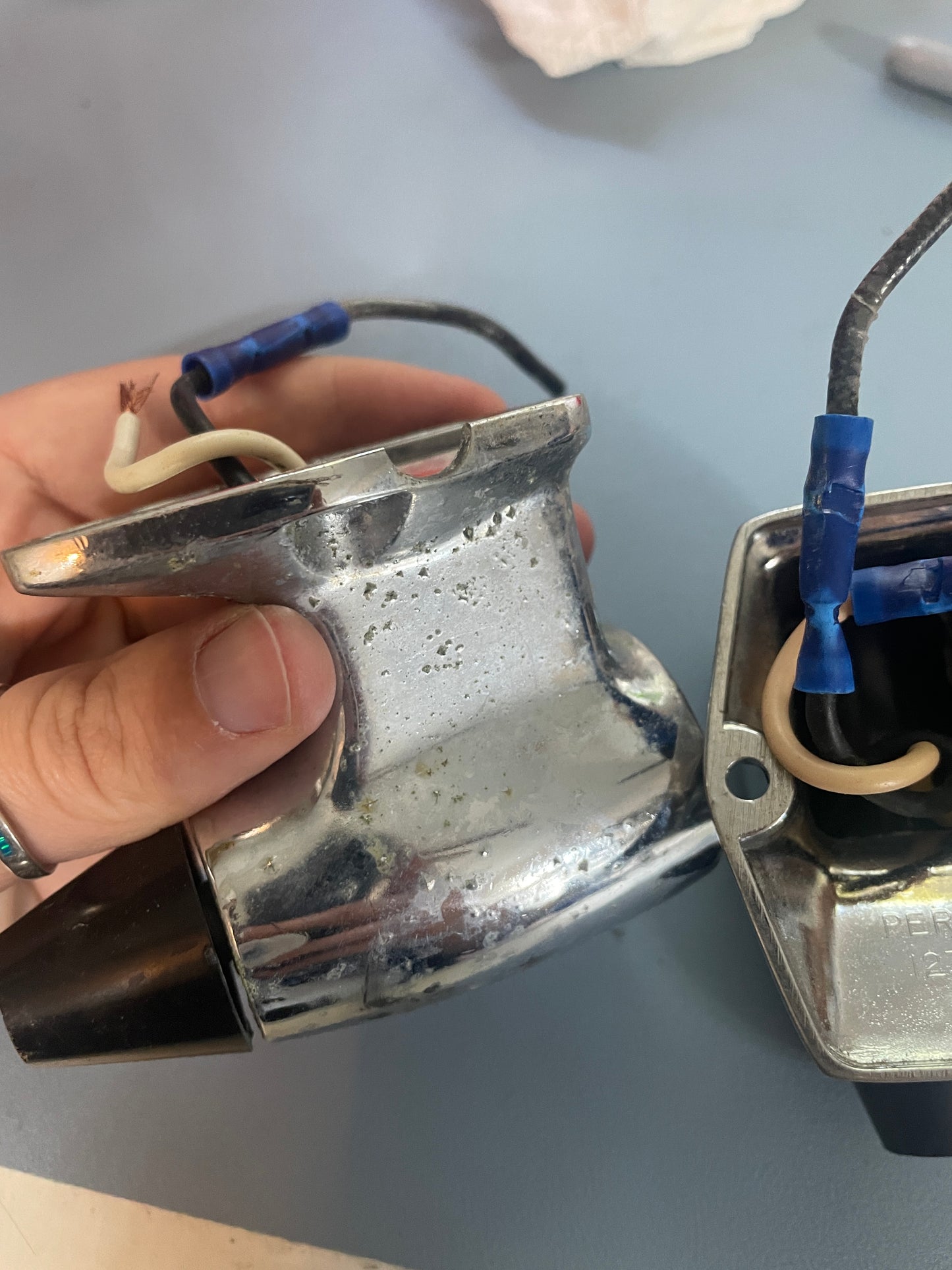 Metallic device with wires held by a hand against a neutral background
