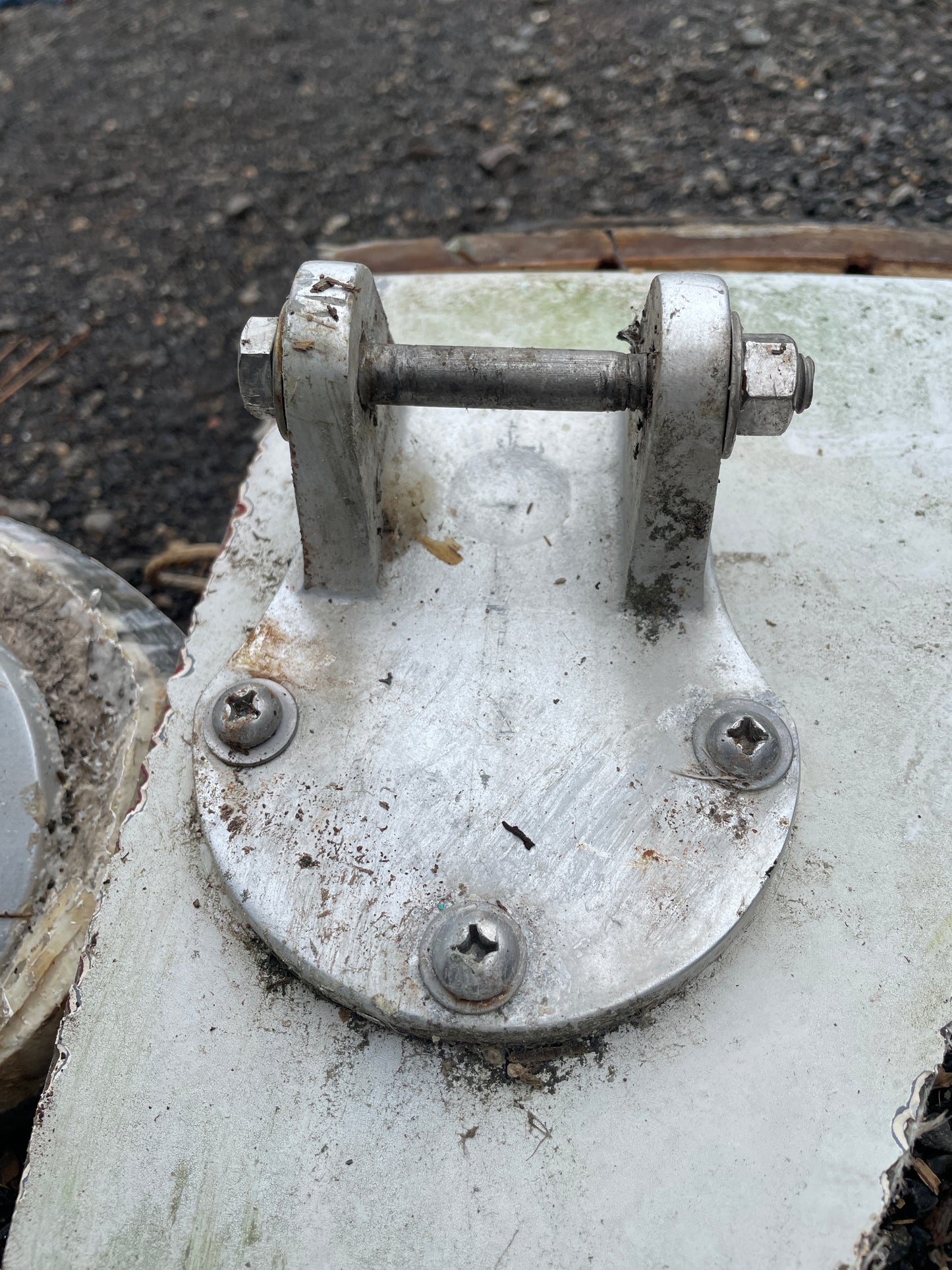 Close-up of a metal valve or fitting with visible rust and wear on a concrete surface.