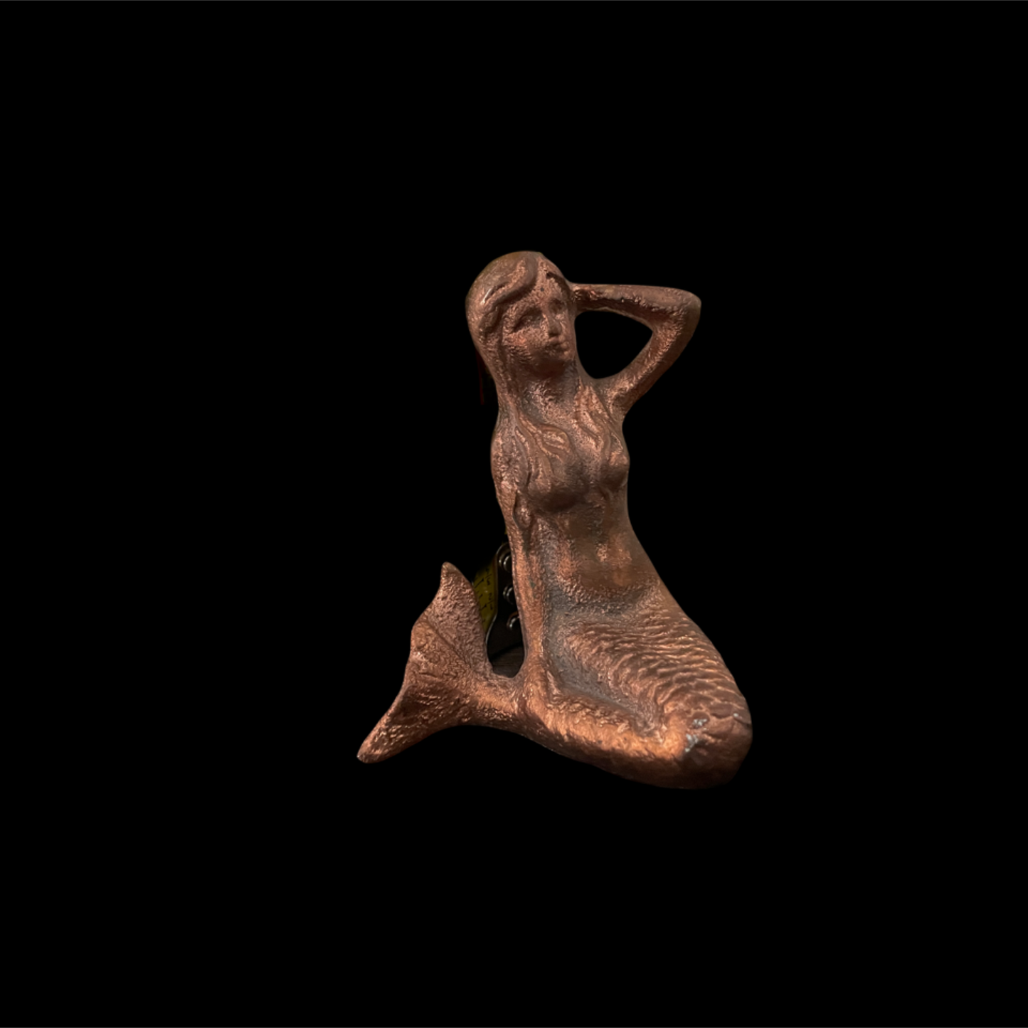 Bronze mermaid figurine on a black background