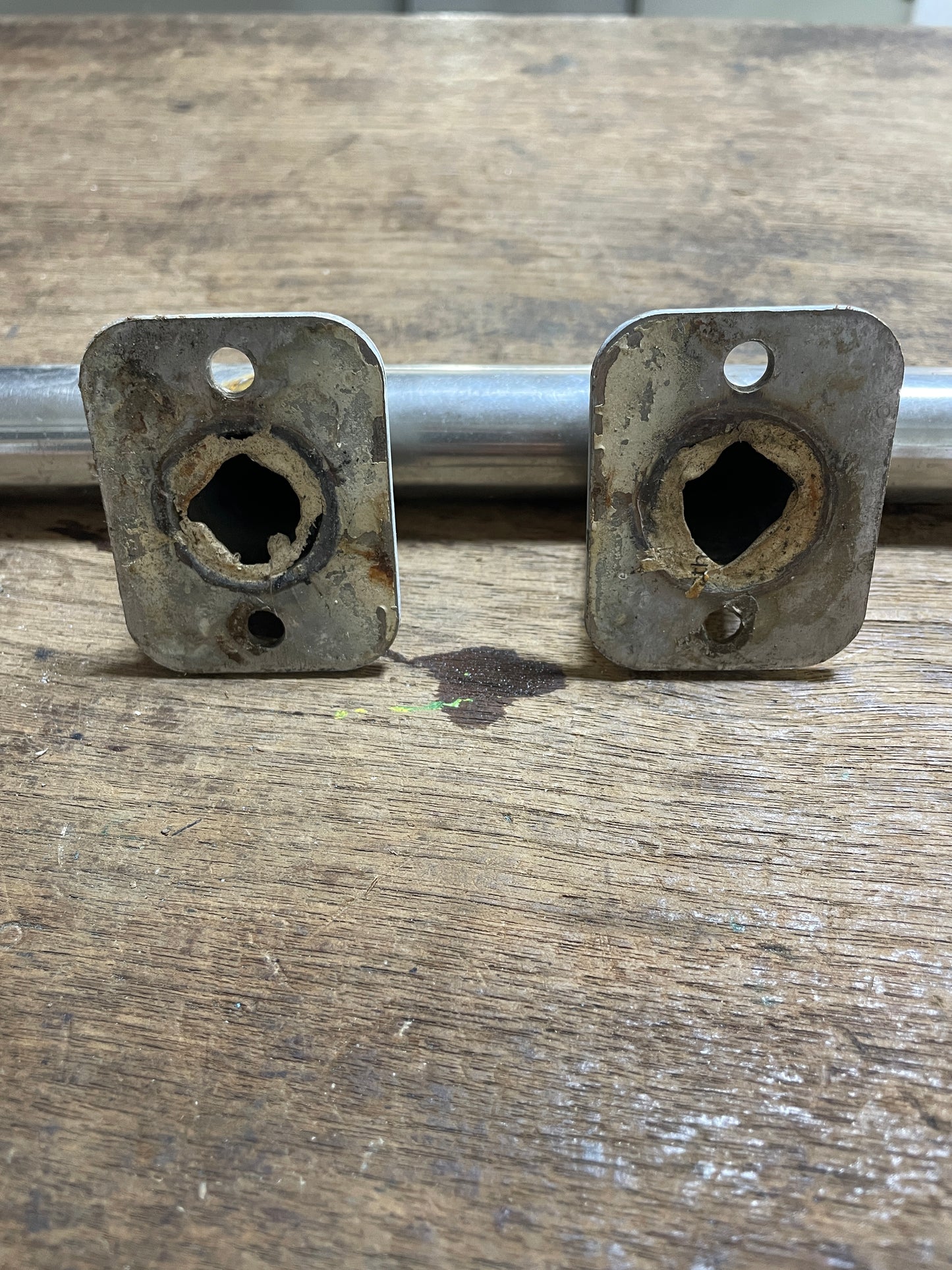 Two metal brackets with holes on a wooden surface