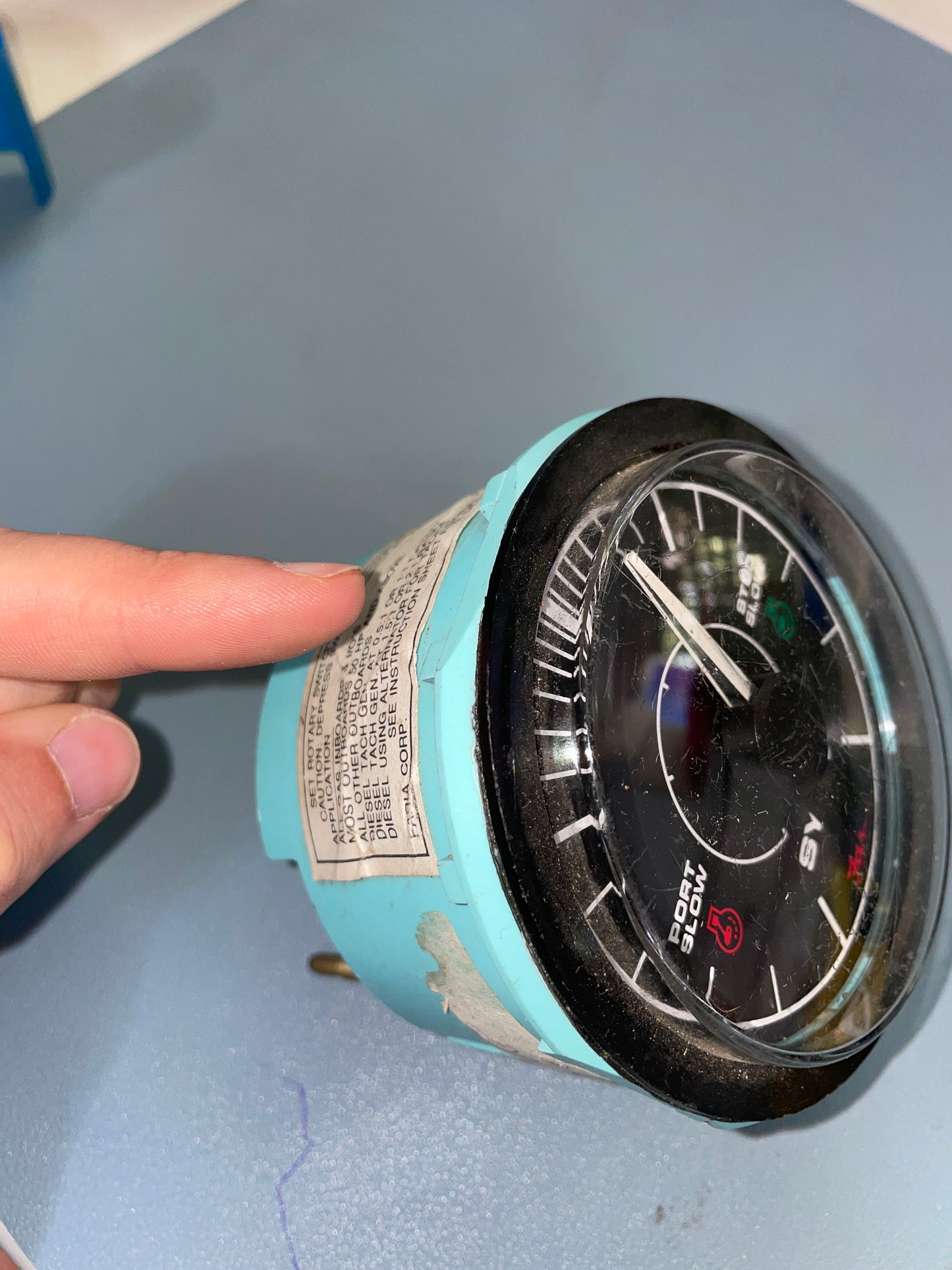 Mechanical pressure gauge with a finger pointing at it on a gray background