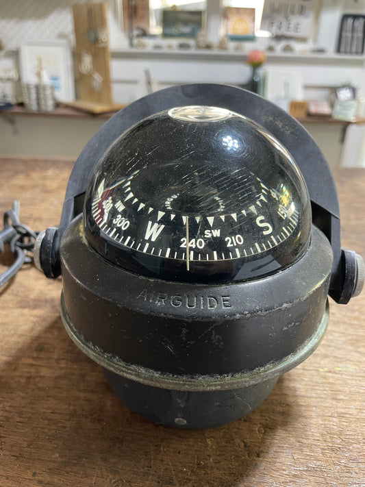 Black compass mounted on a wooden surface with a blurred background