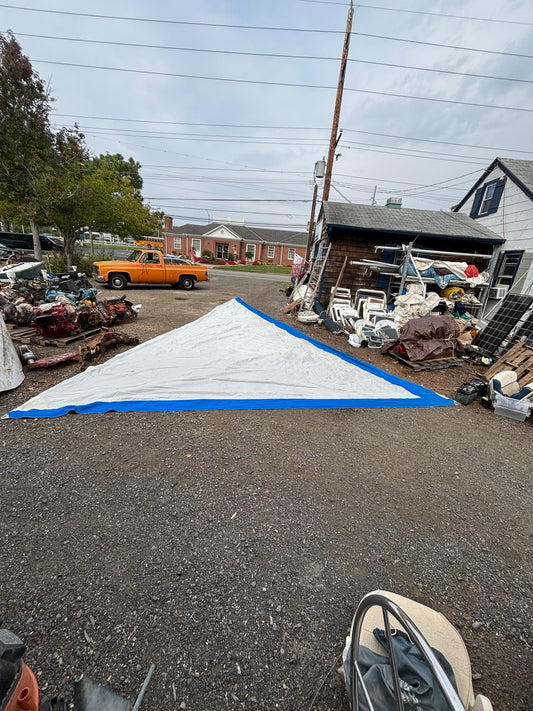Boat on a trailer with a white tarp covering it, parked on a street.