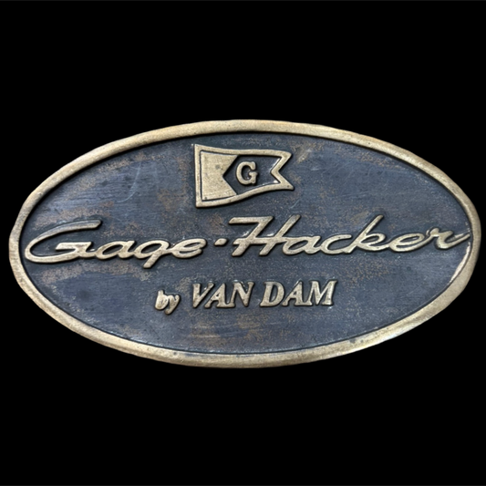 Enameled metal badge with 'Gage Hacker by Van Dam' text on a black background