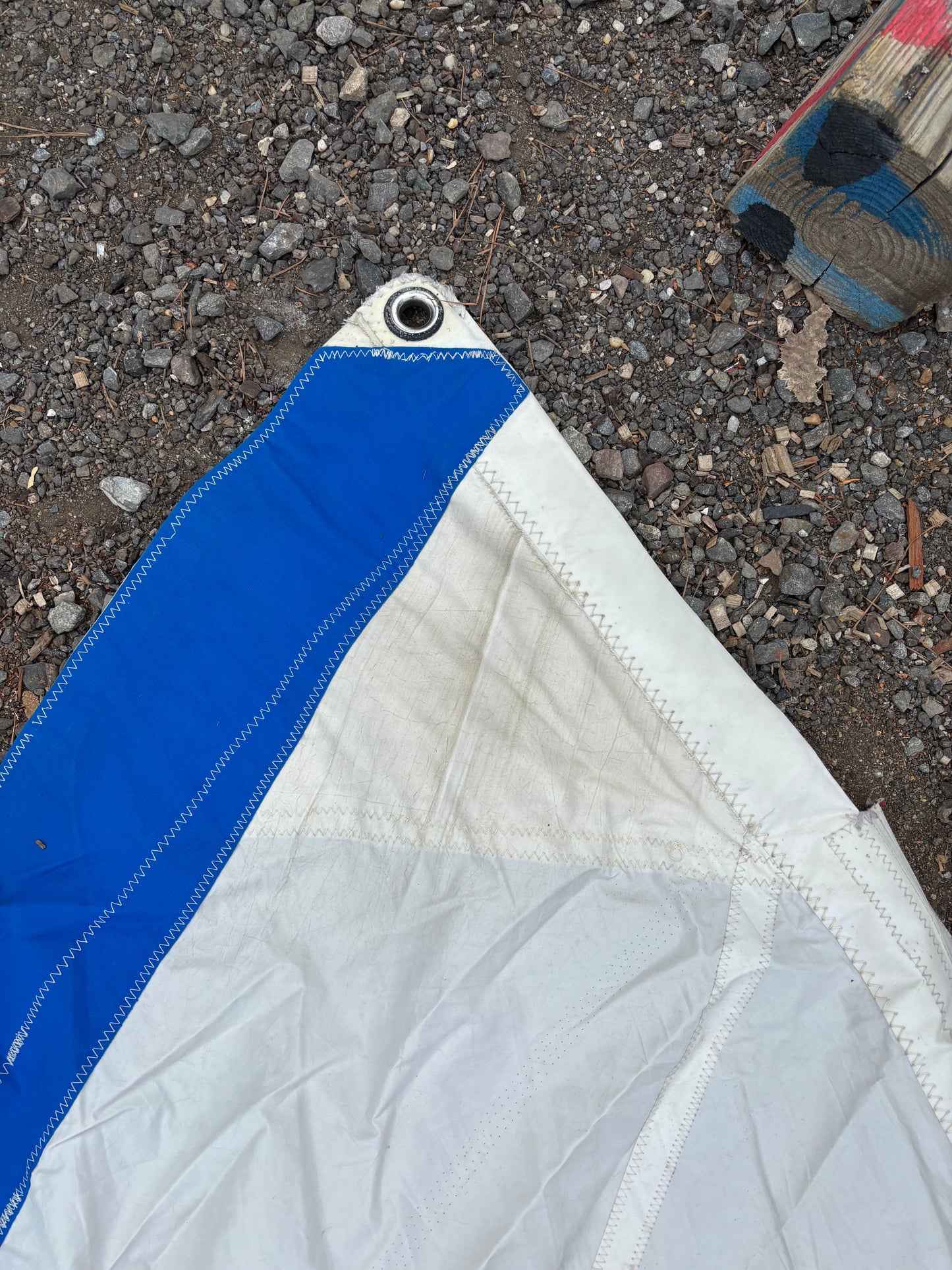 Close-up of a white and blue tarp on a gravel surface