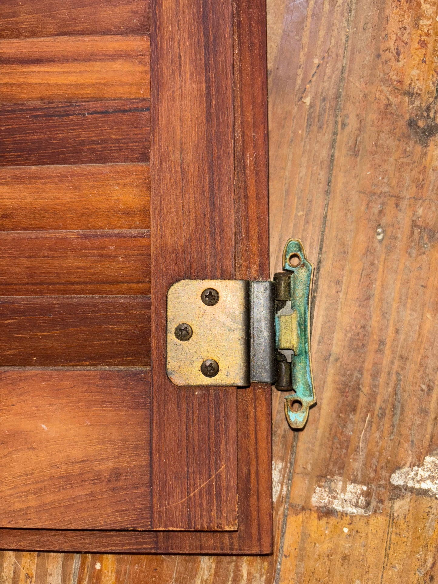 Close-up of a wooden panel with a metal hinge on a wooden background