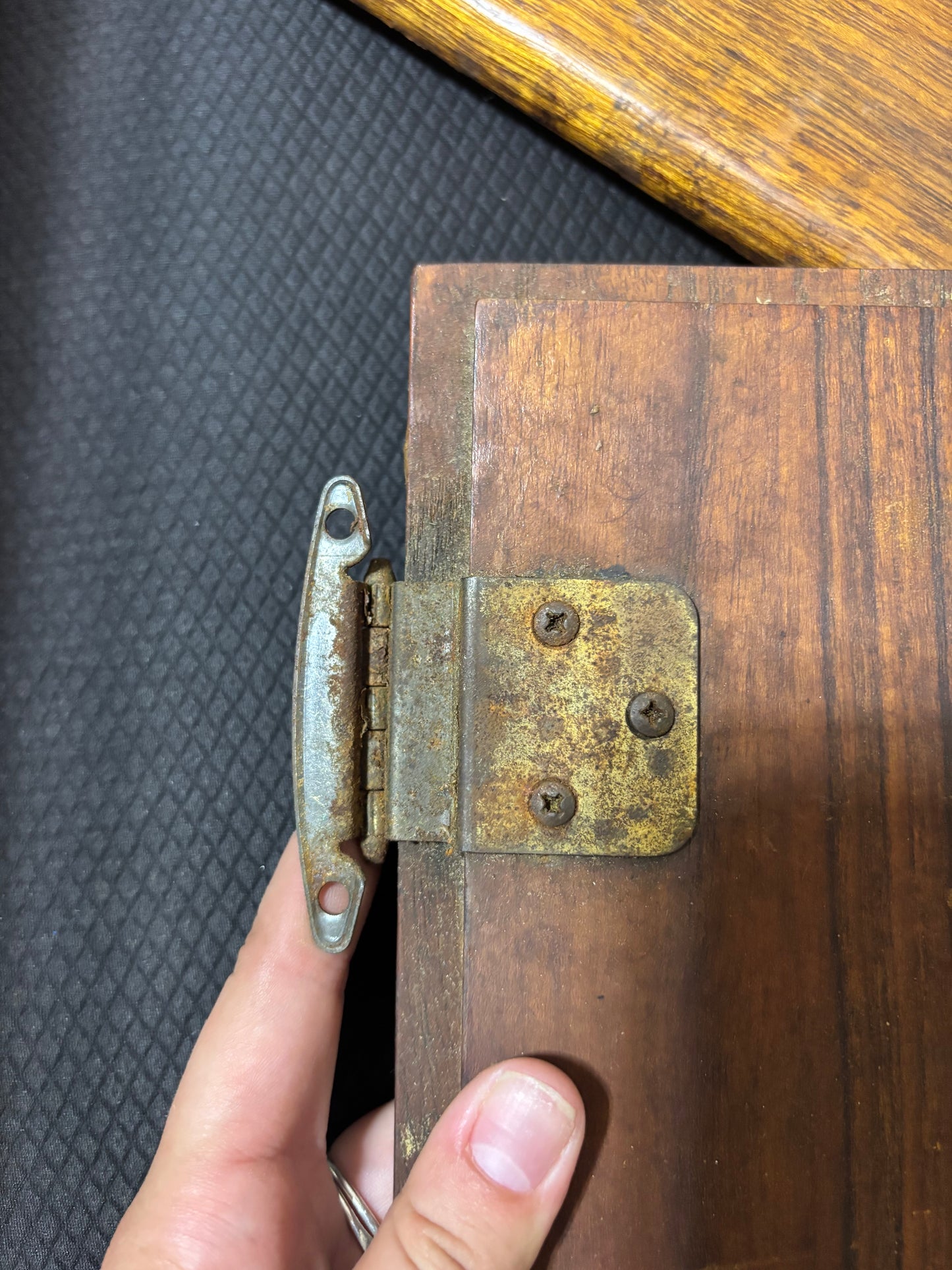 Close-up of a rusty metal hinge on a wooden surface