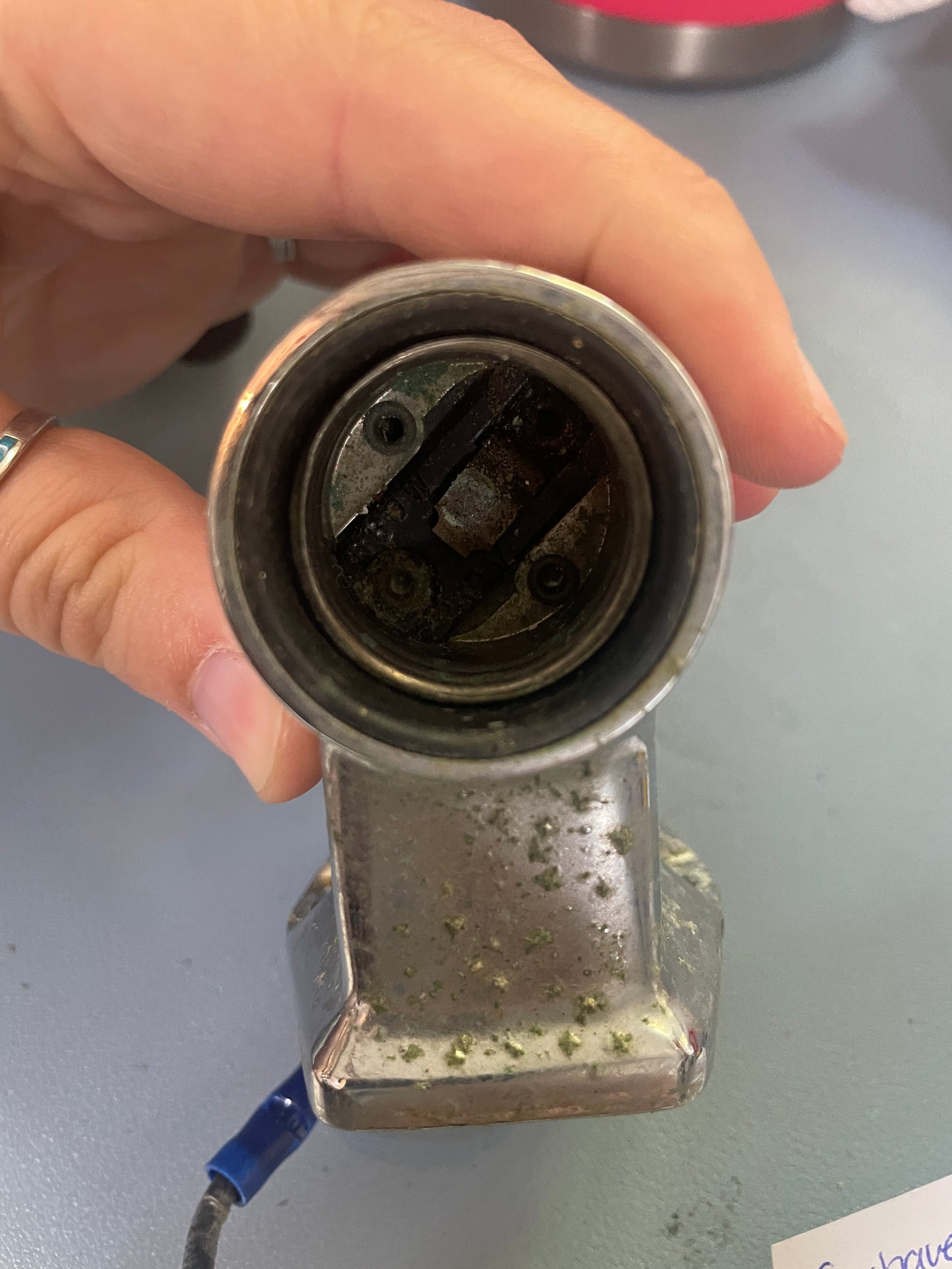 Metal vehicle connector held by a hand against a gray background