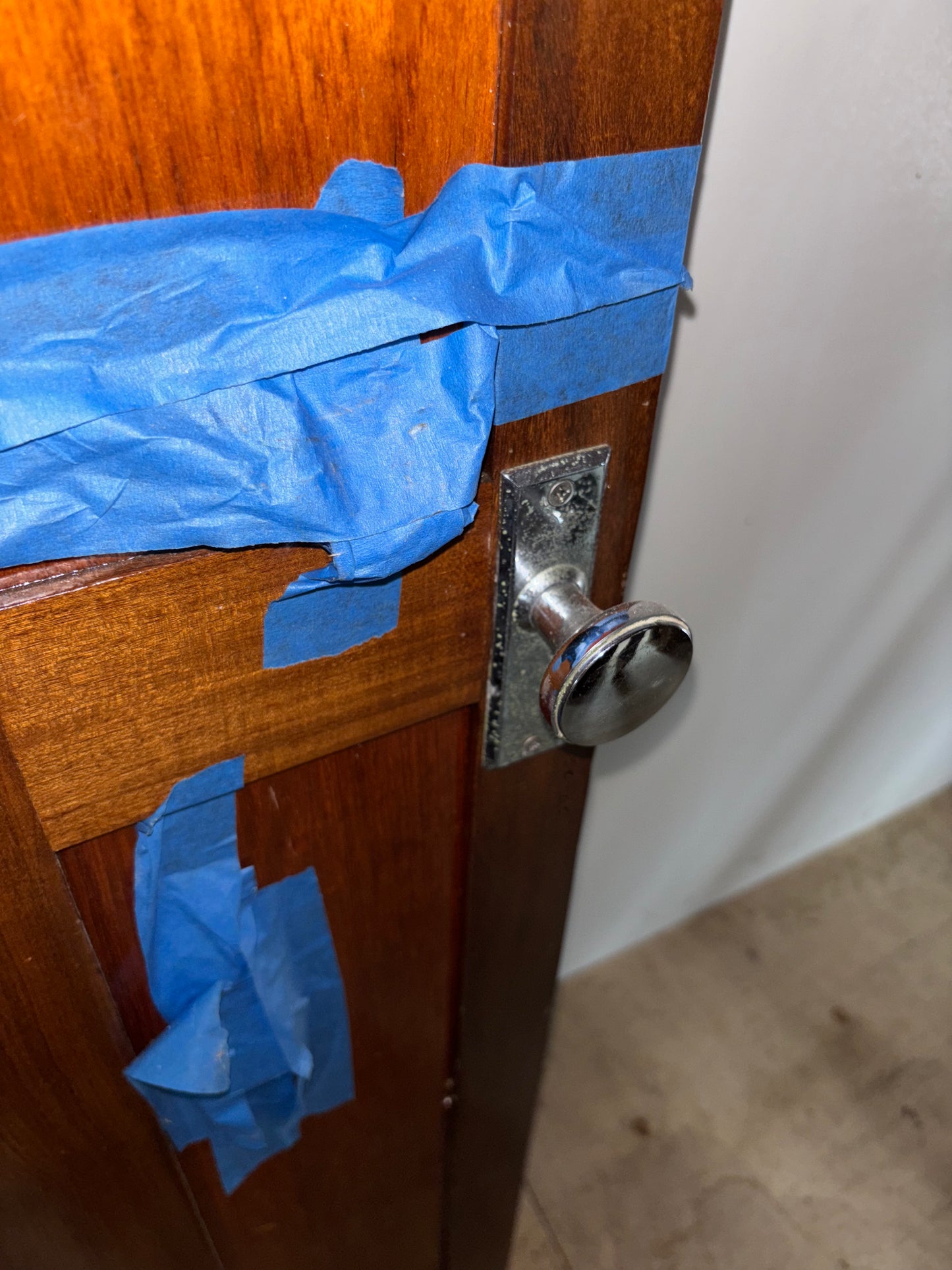 Wooden door with blue tape and a metal doorknob