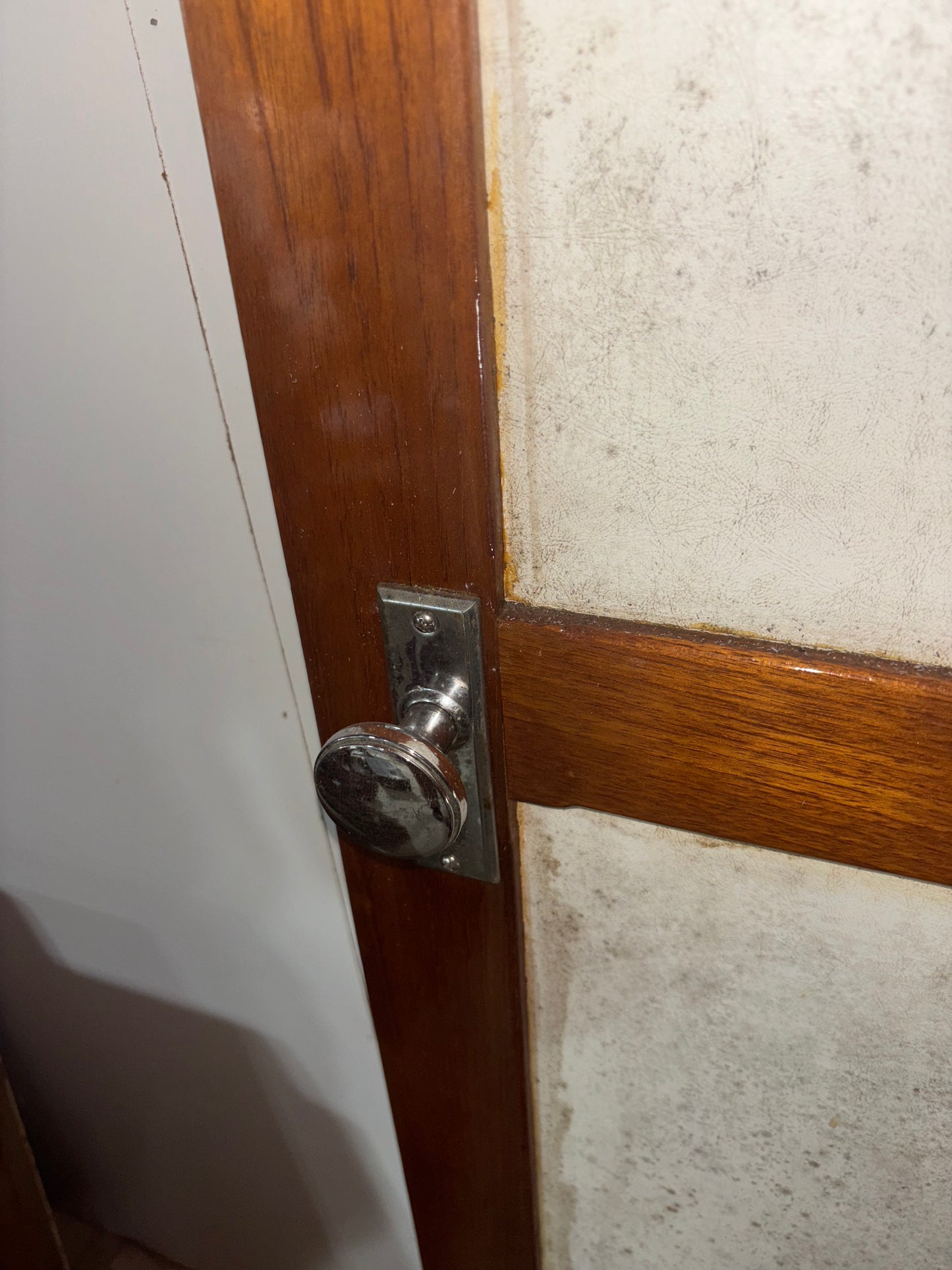 Close-up of a door handle on a wooden door with a textured wall background