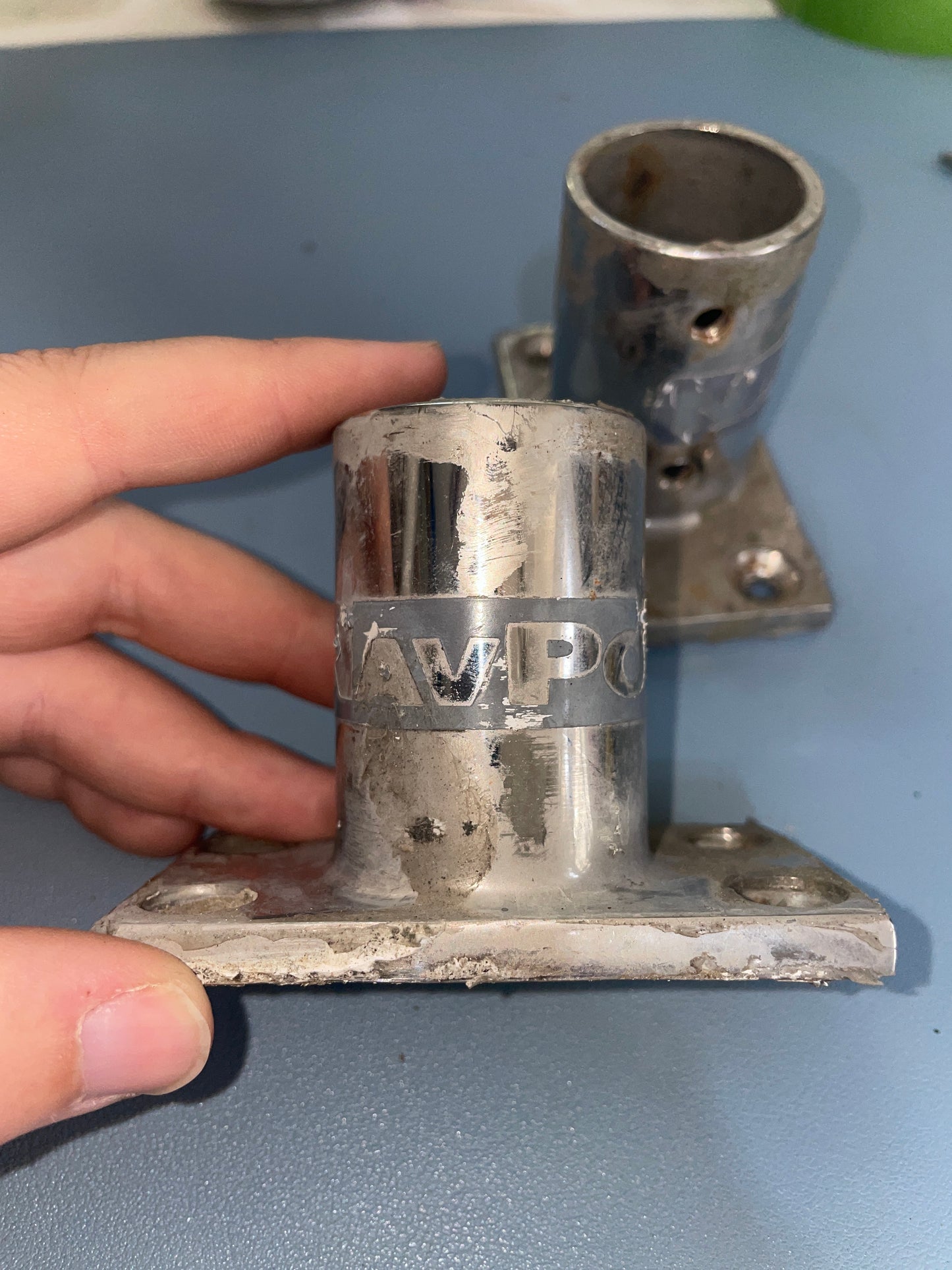 Metal pipe fitting held by a hand against a gray background