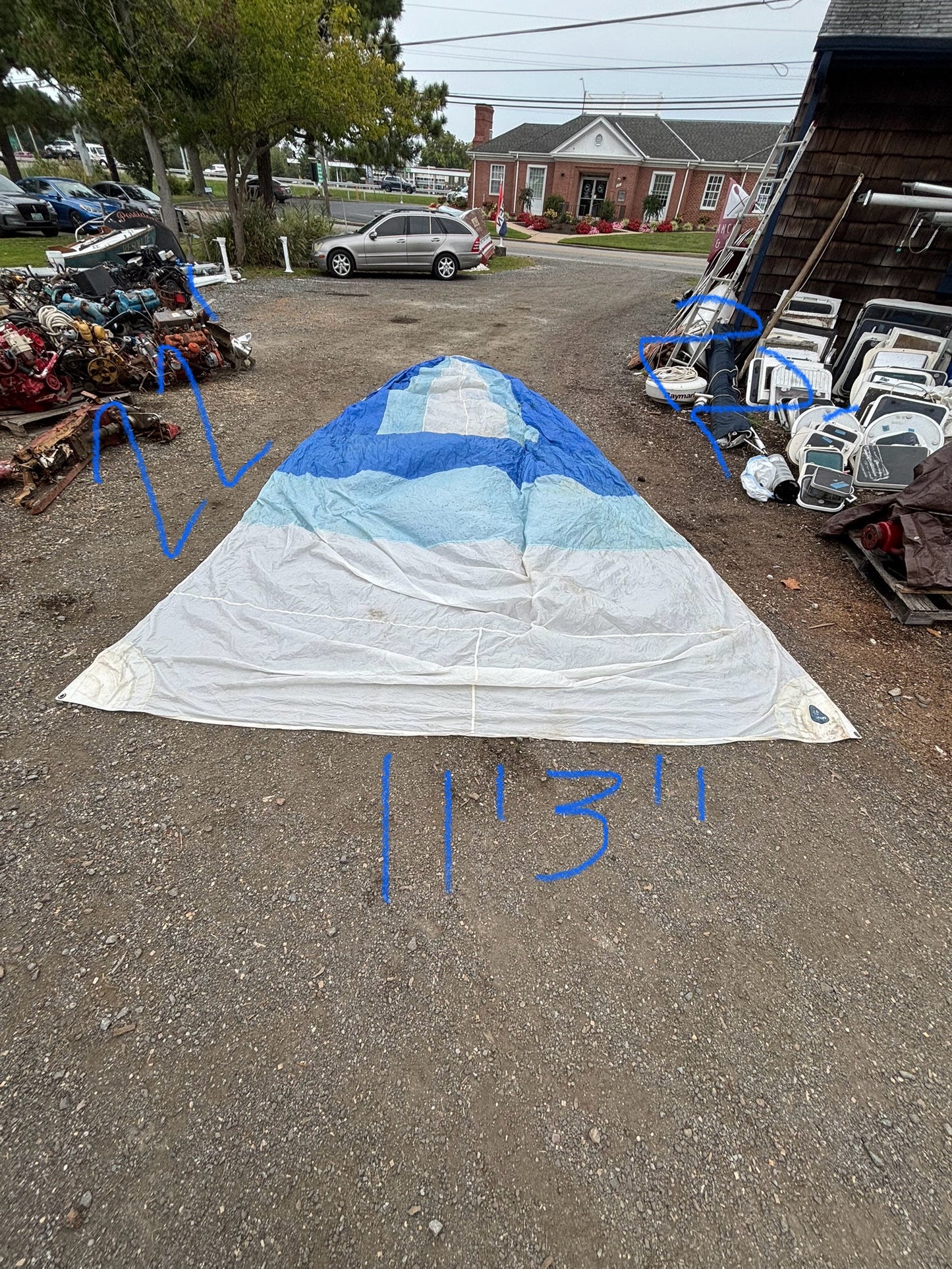 White sail with blue top on a gravel surface, surrounded by other items.