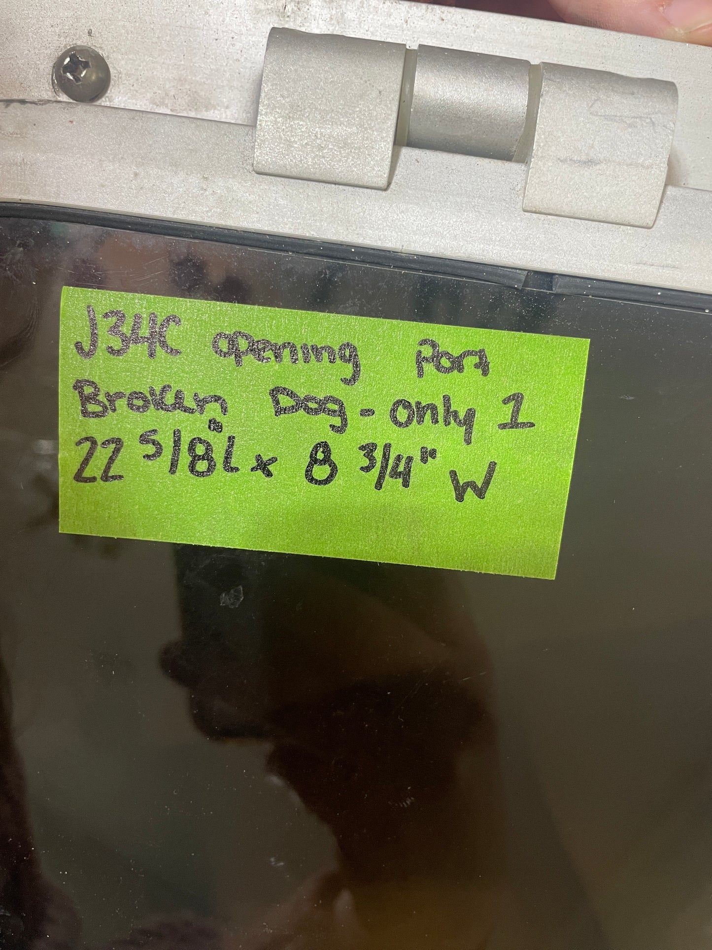 Metallic object with a green label and measurement details, against a reflective surface.