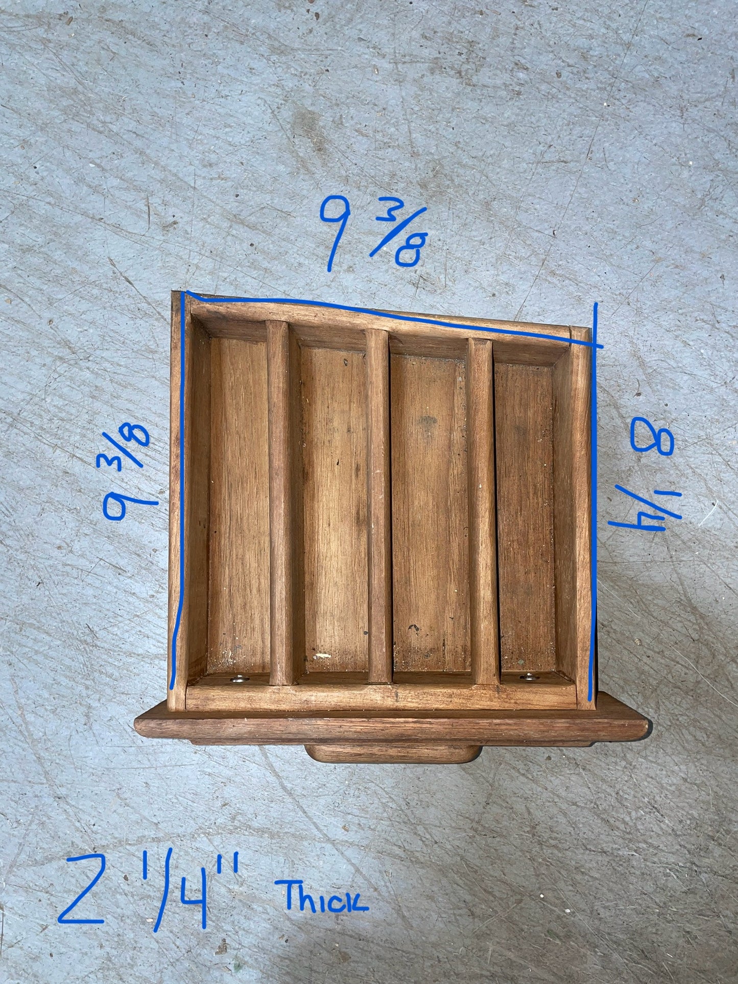 Wooden drawer with measurements marked on a gray surface