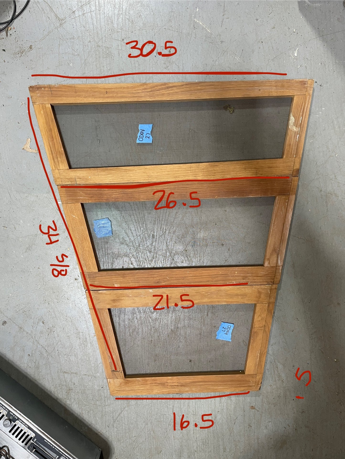 Wooden frames with mesh screens and measurements on a concrete floor