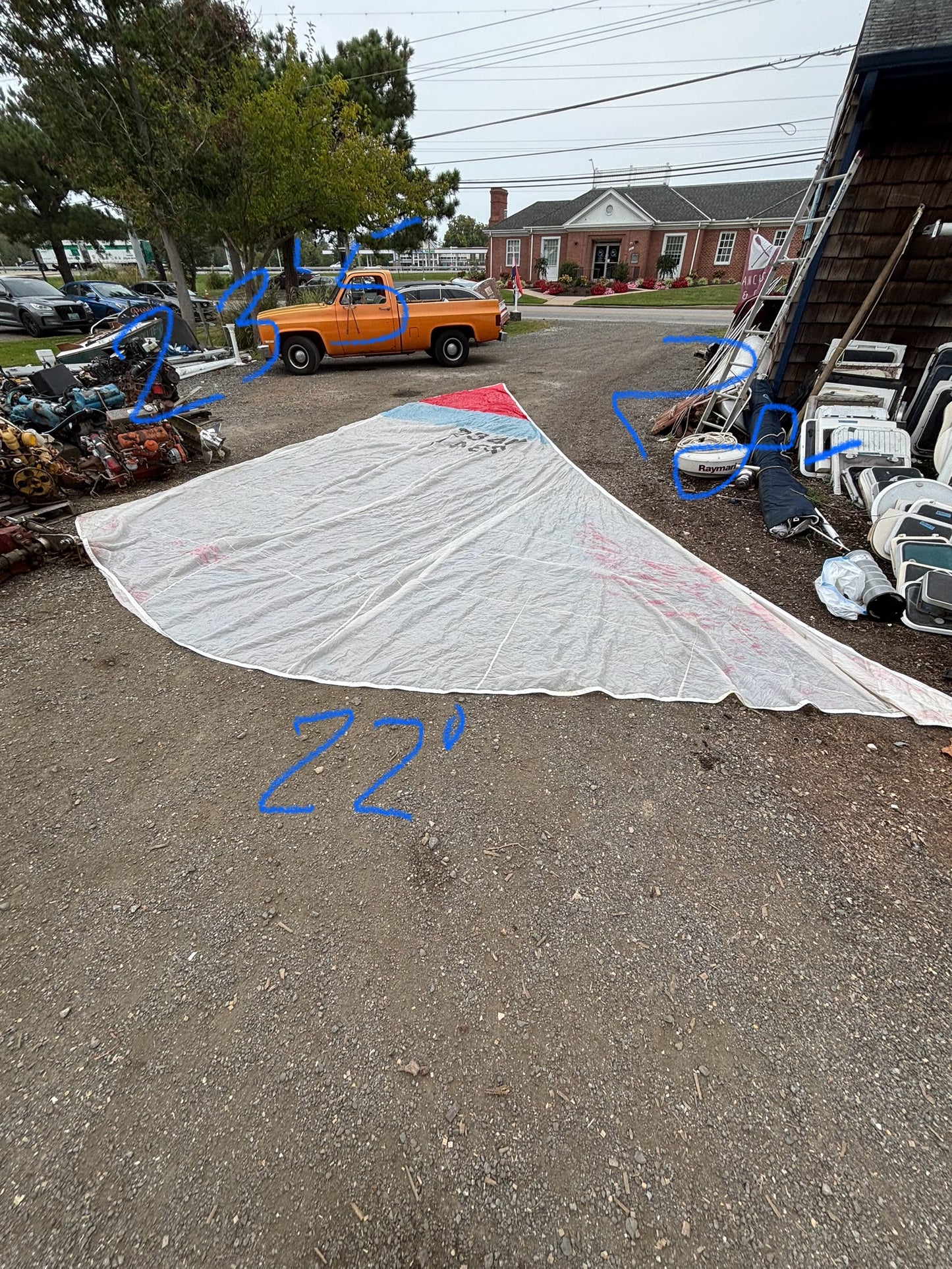 Large white sail or fabric on a driveway with a house and parked cars in the background.