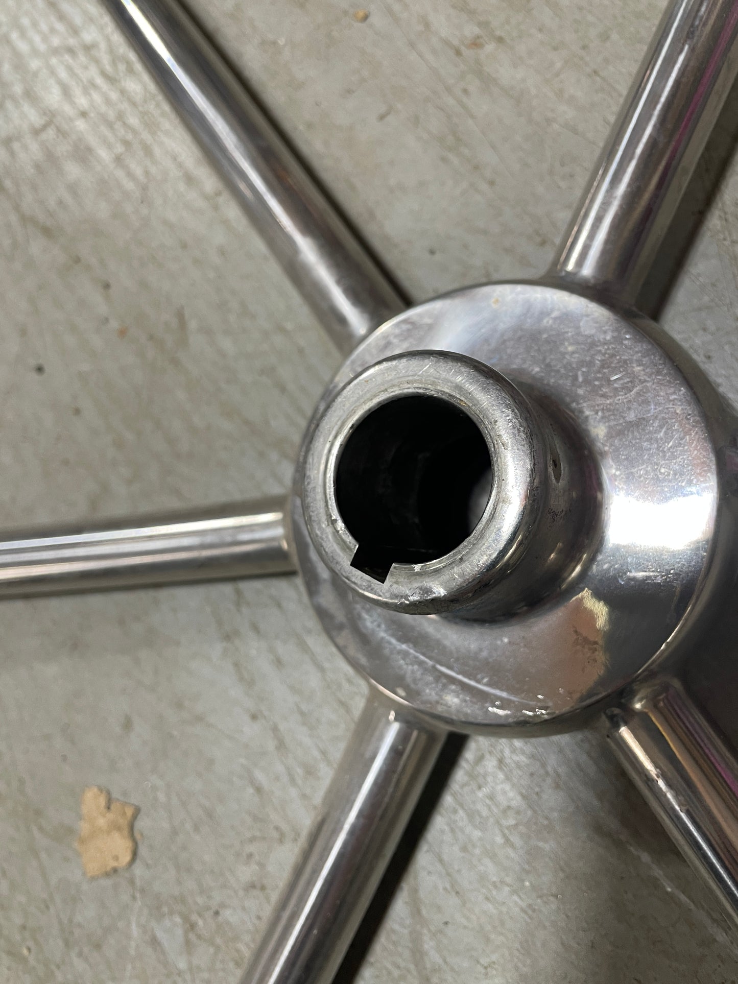 Close-up of a metallic wheel hub with five spokes on a textured surface