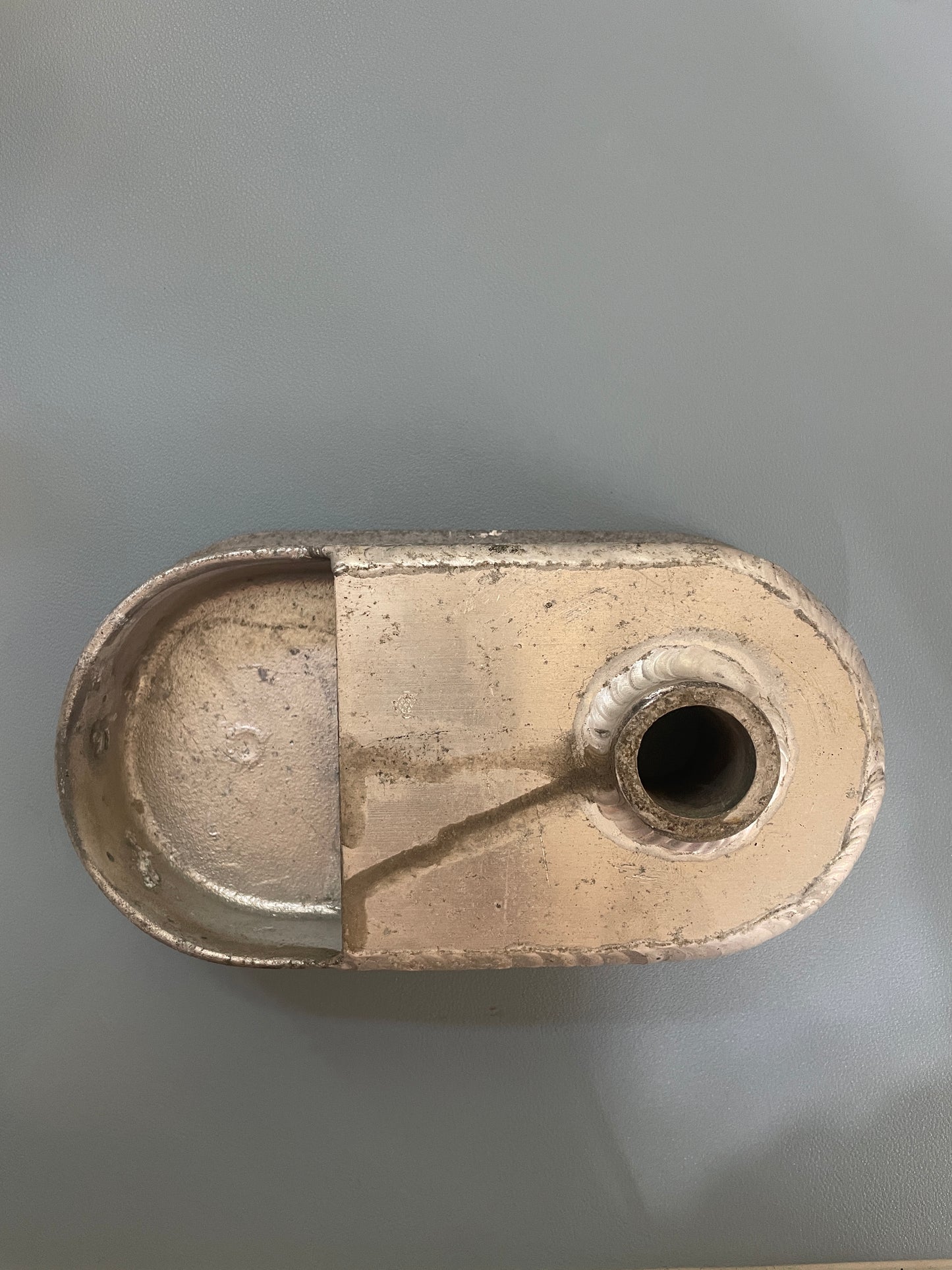 Metallic object with a cylindrical hole on a gray background