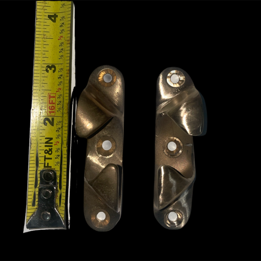 Two brass brackets with a measuring tape on a black background